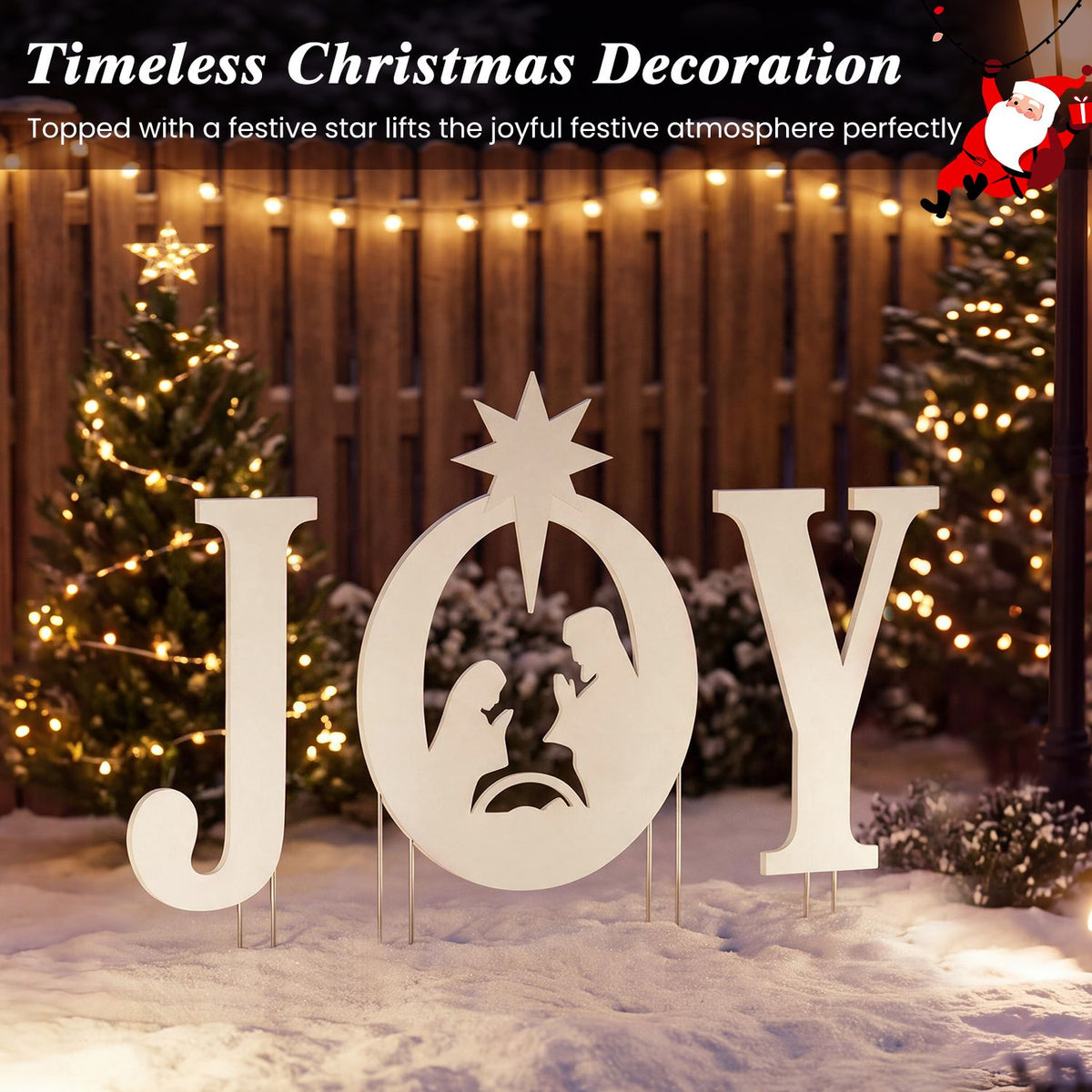 Cream JOY nativity sign with a star standing in snow among Christmas lights.