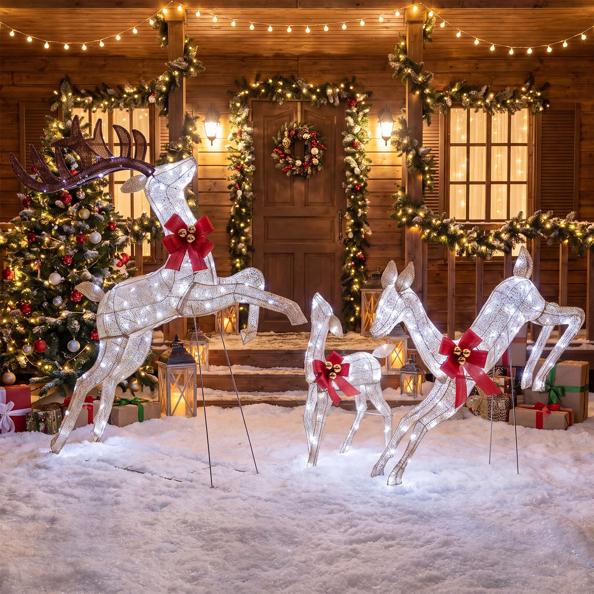 Three glowing reindeer with red bows stand in snowy ground outside a decorated wooden home.