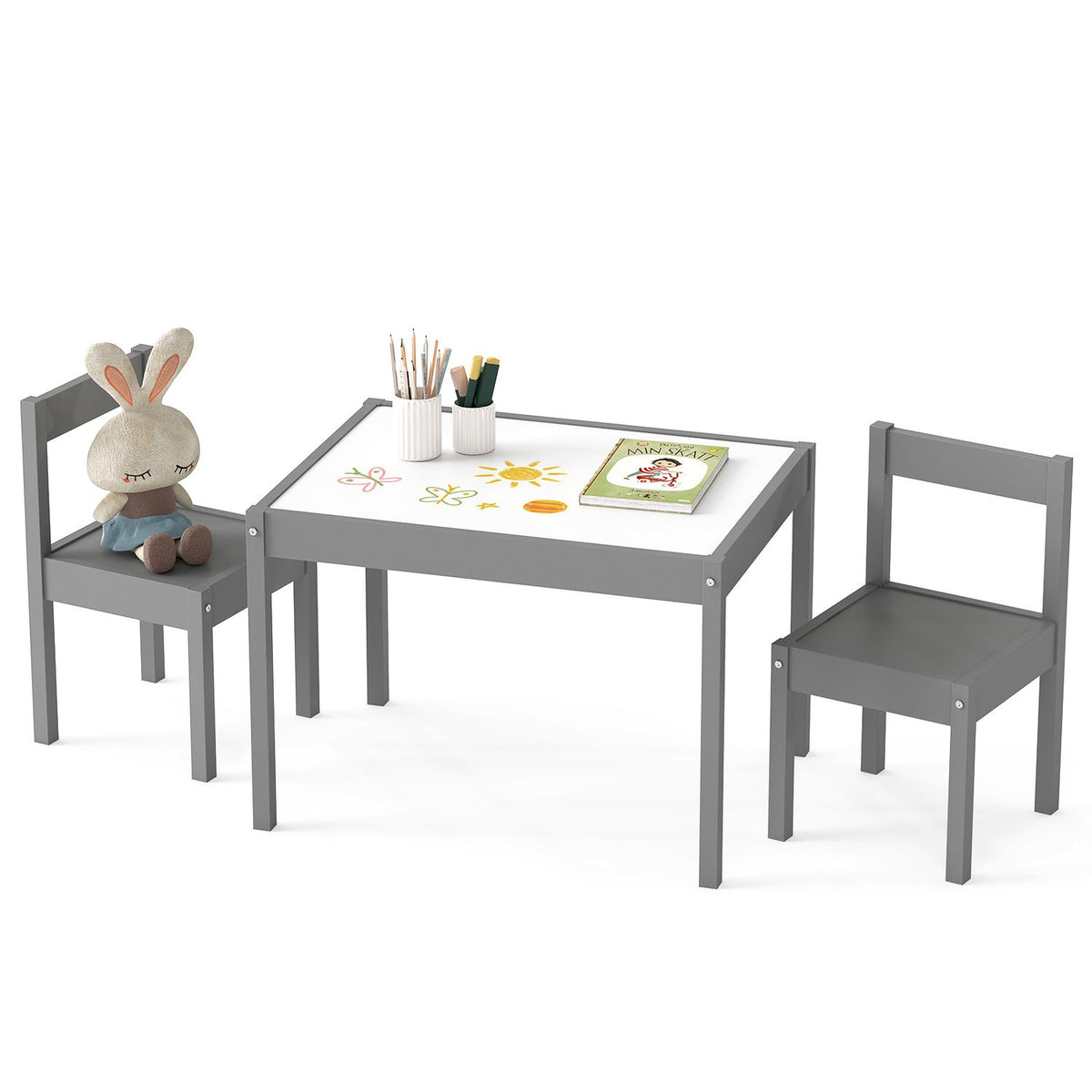 Gray toddler table and two chairs with a plush rabbit, pencils, and a book against white.