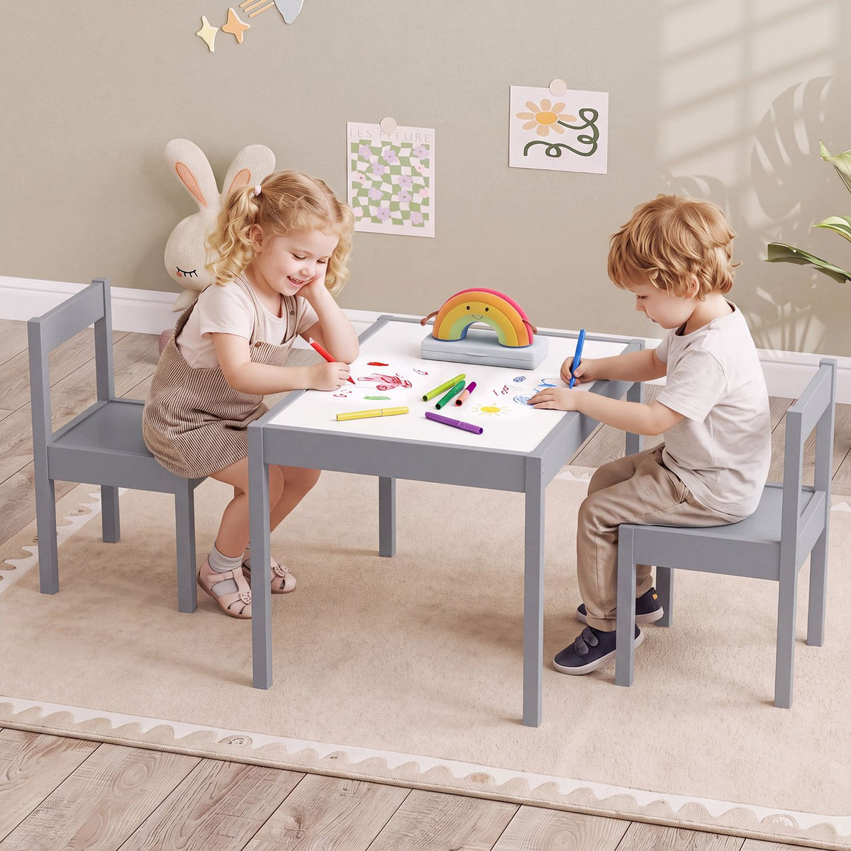 Two children draw at a gray toddler table with matching chairs in a bright playroom.