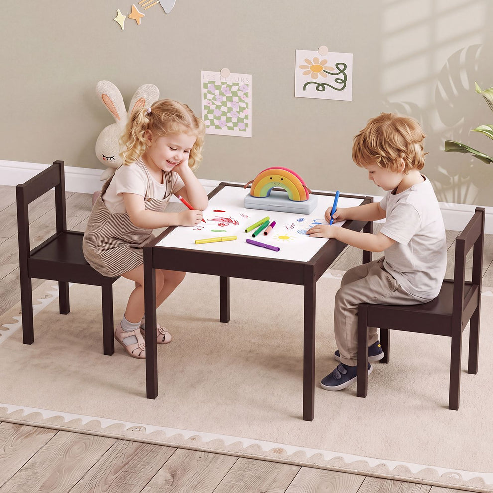 Two children draw at a dark wood table with matching chairs in a bright playroom.