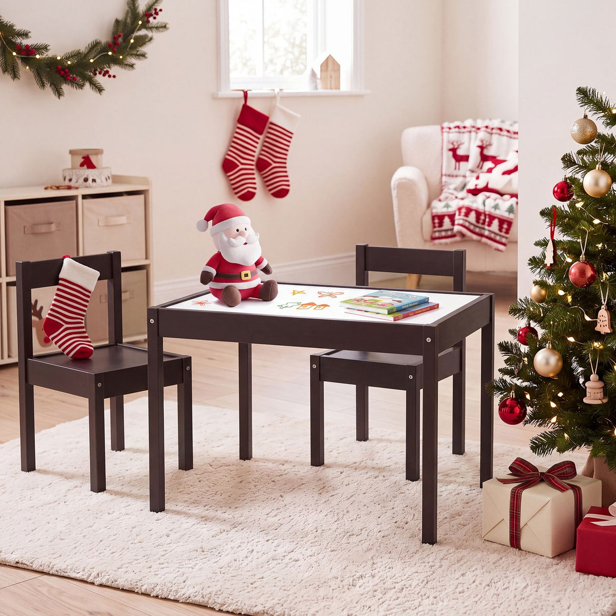 A dark wood table and two matching chairs sit among Christmas decorations, with books and a Santa toy on top.