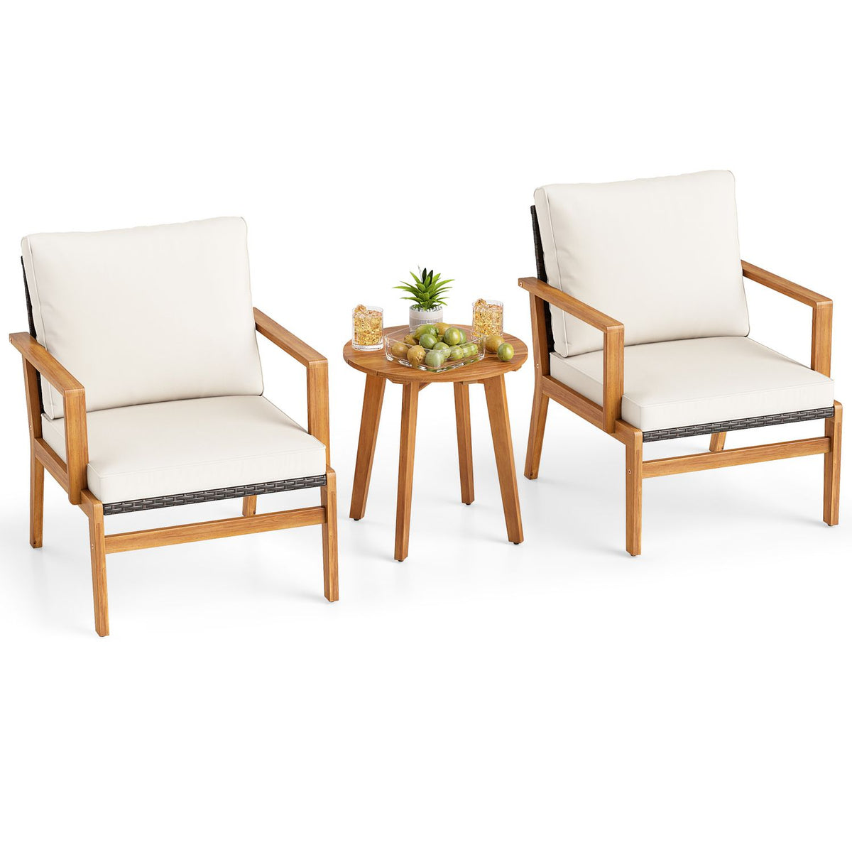 Two cushioned armchairs and a round table topped with fruit, drinks, and a small plant.