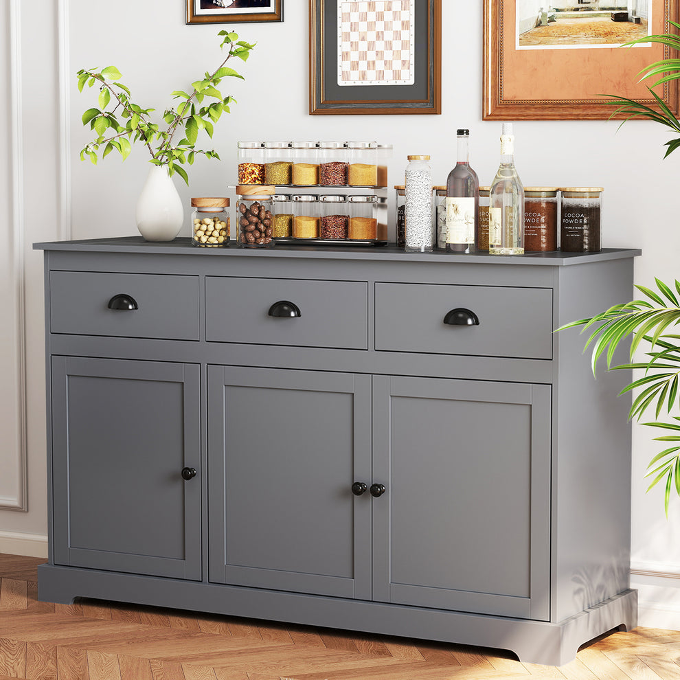 Gray sideboard with three drawers and three cabinet doors, styled with jars and bottles in a bright room.