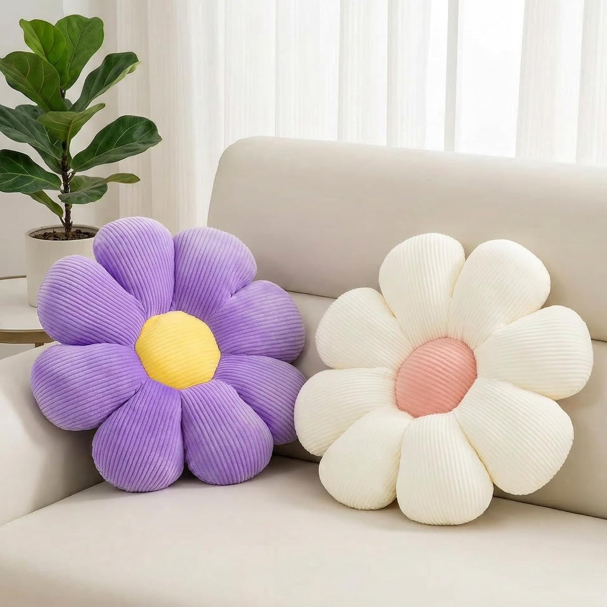 Close-up of purple and cream daisy throw pillows arranged on a beige sofa, angled living-room view