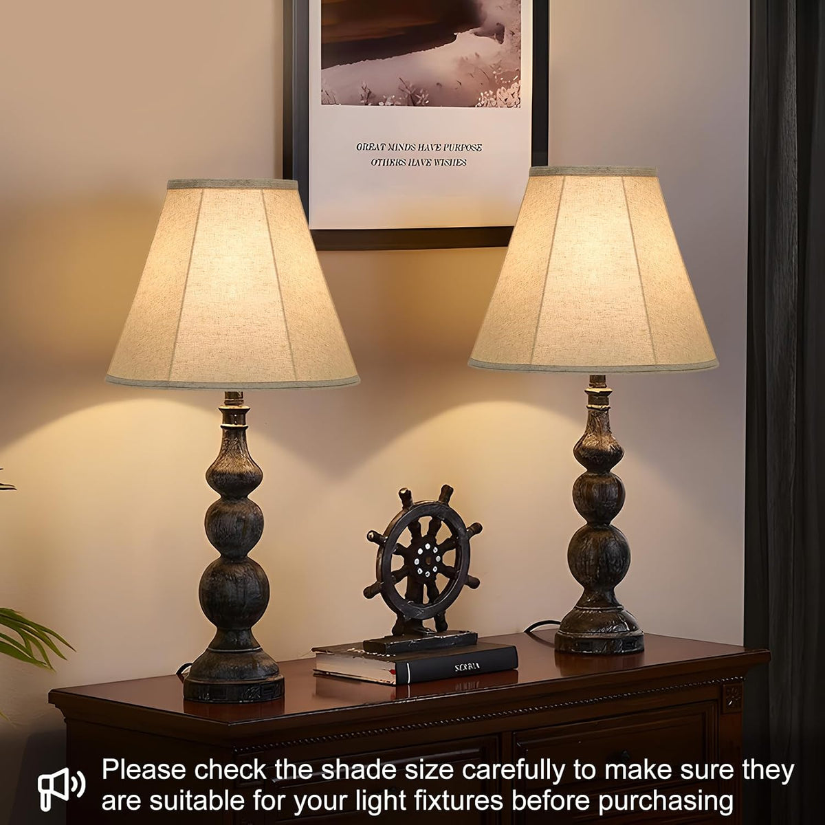 Two lit table lamps with bell lampshades on a console table in a living room setting