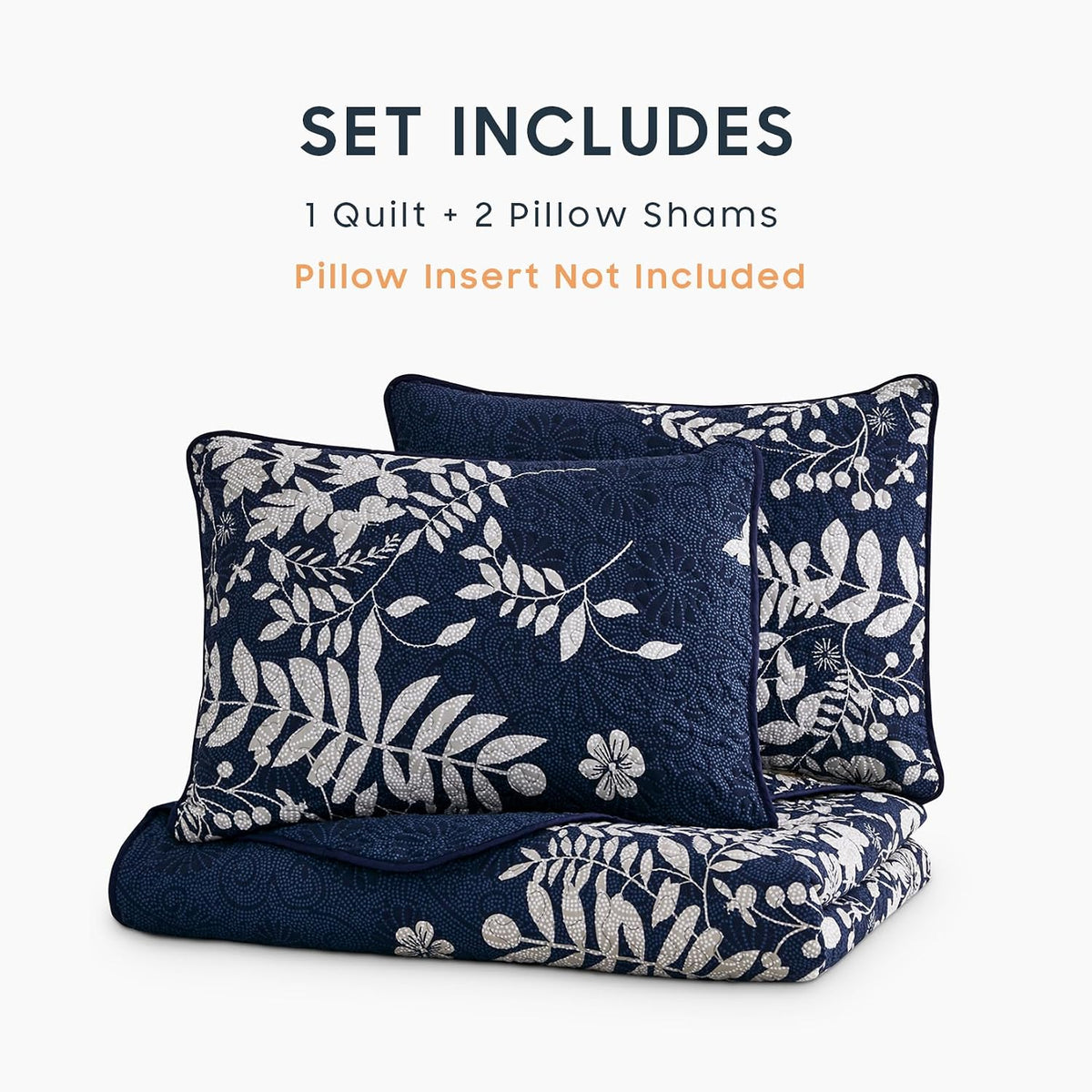 Folded navy floral quilt with two matching pillow shams stacked on a white background in studio layout