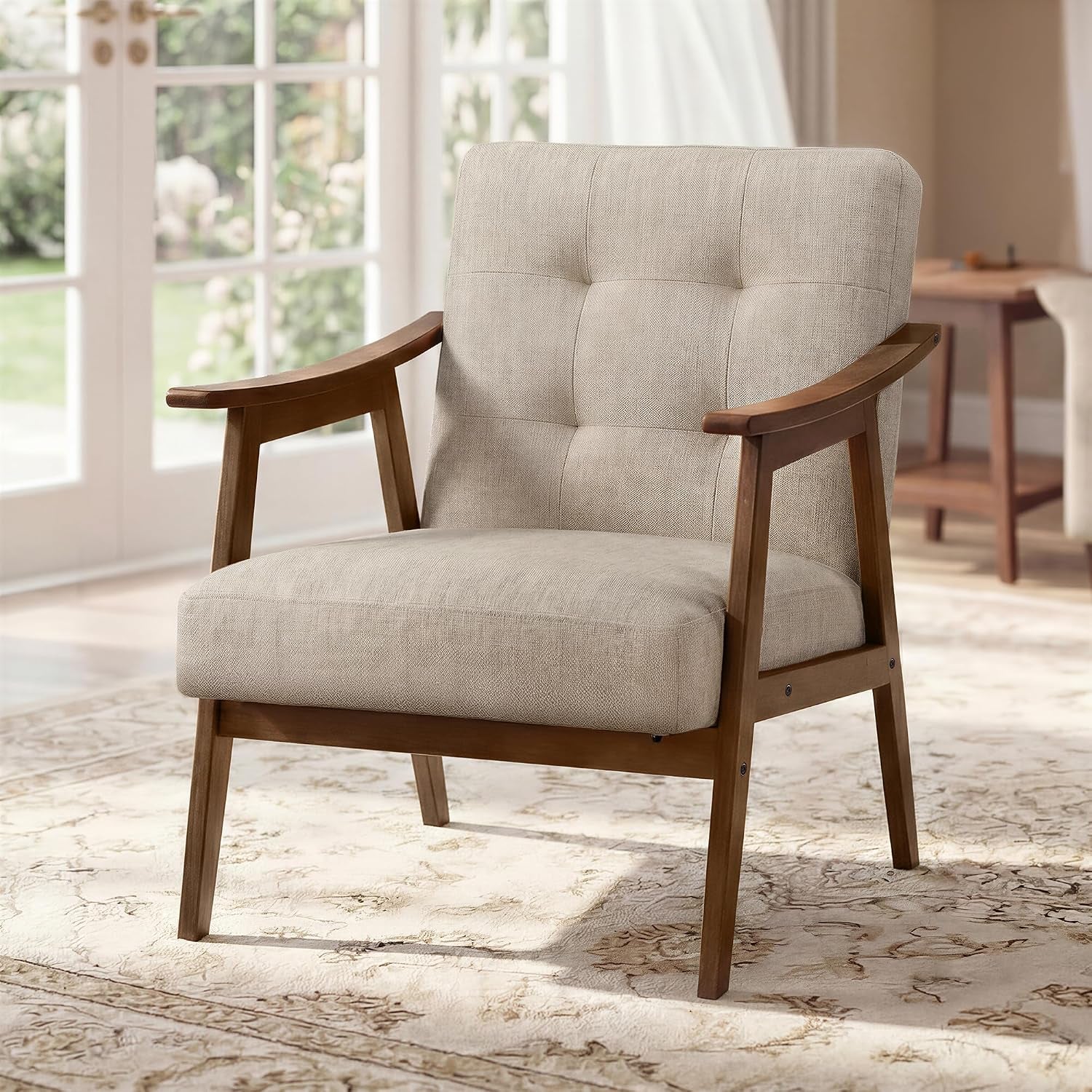 Beige button-tufted mid-century armchair with wooden frame in a sunlit living room.