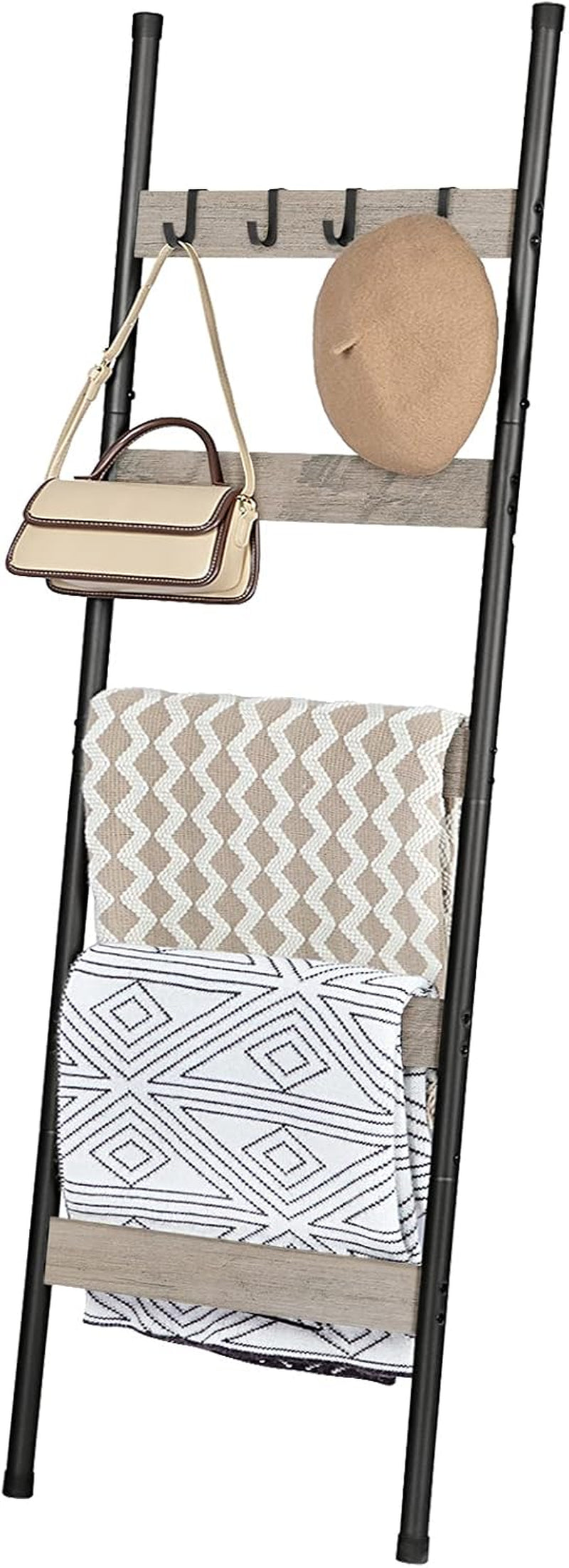 Angled full view of ladder with greige shelves, black metal rails and two folded patterned throws draped over rungs