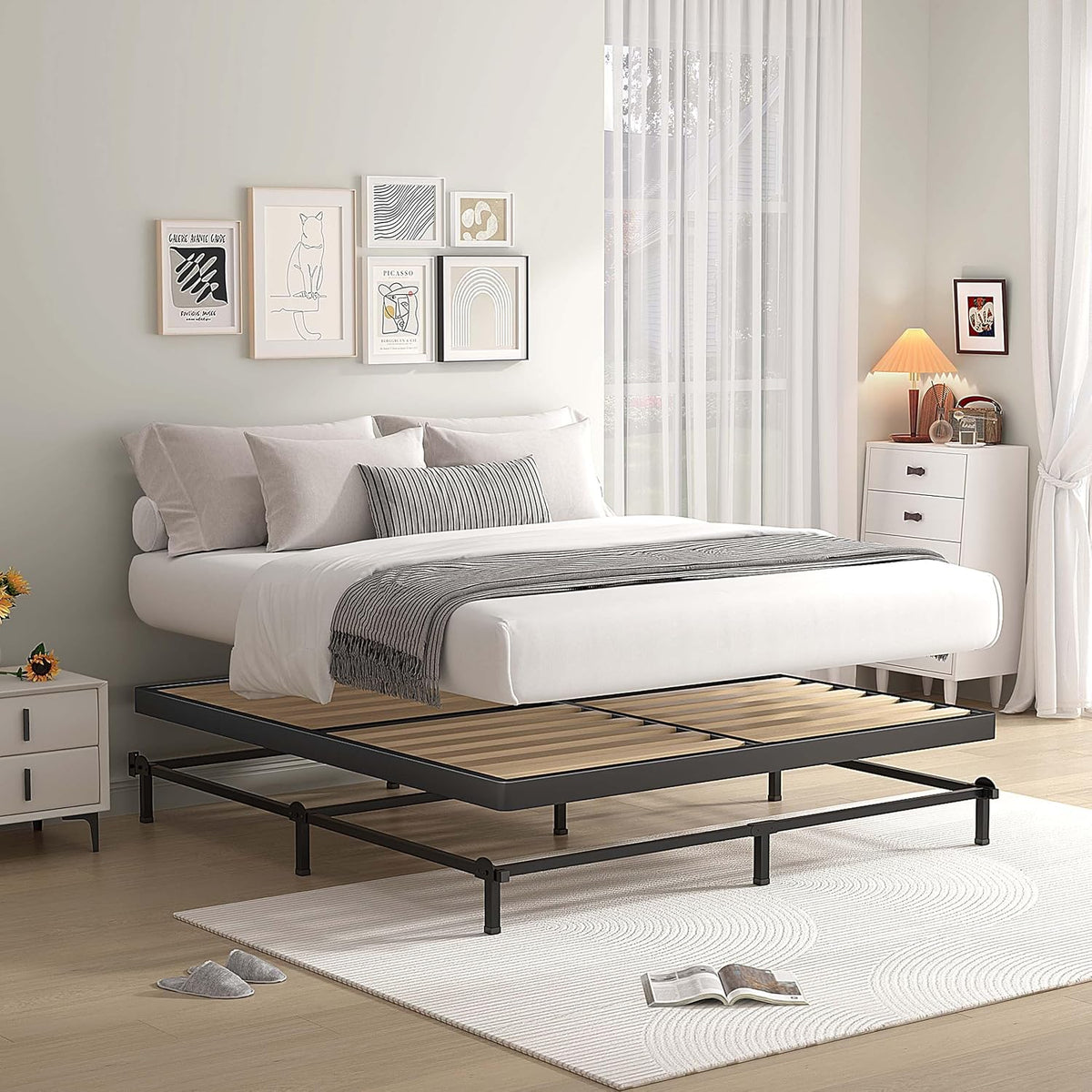Side view of a low black metal bed frame with wooden slats and mattress slightly raised above the frame