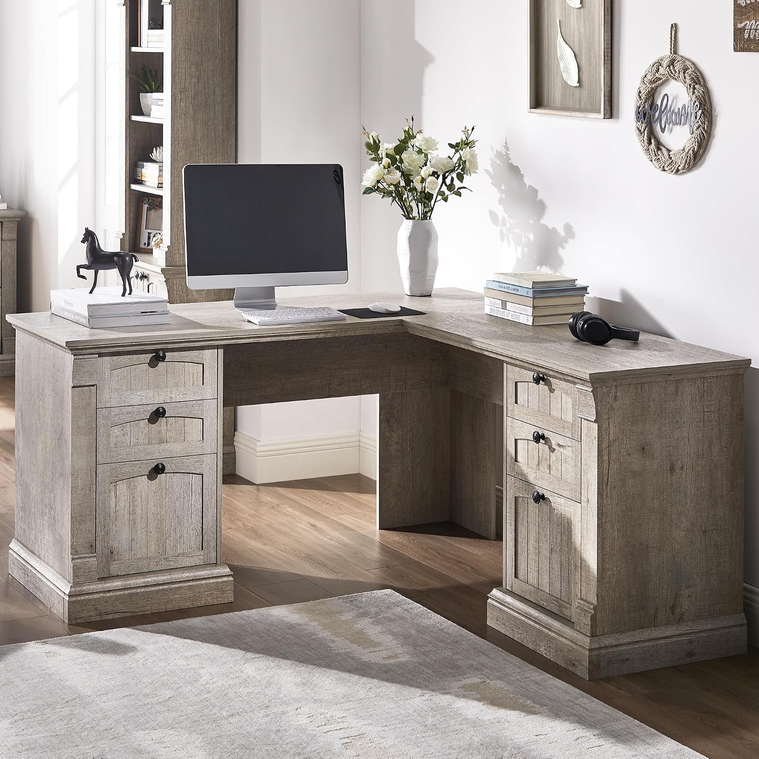 L-shaped corner desk in light gray wood finish styled with monitor and vase on top