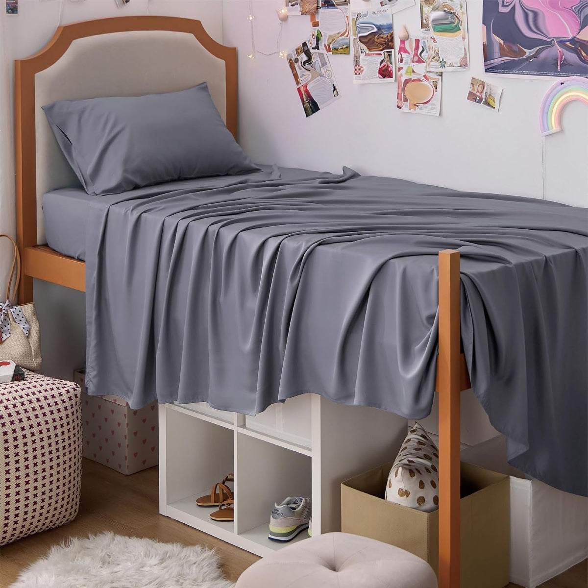 Side view of a raised bed with a draped gray sheet and single matching pillow, storage cubbies beneath.