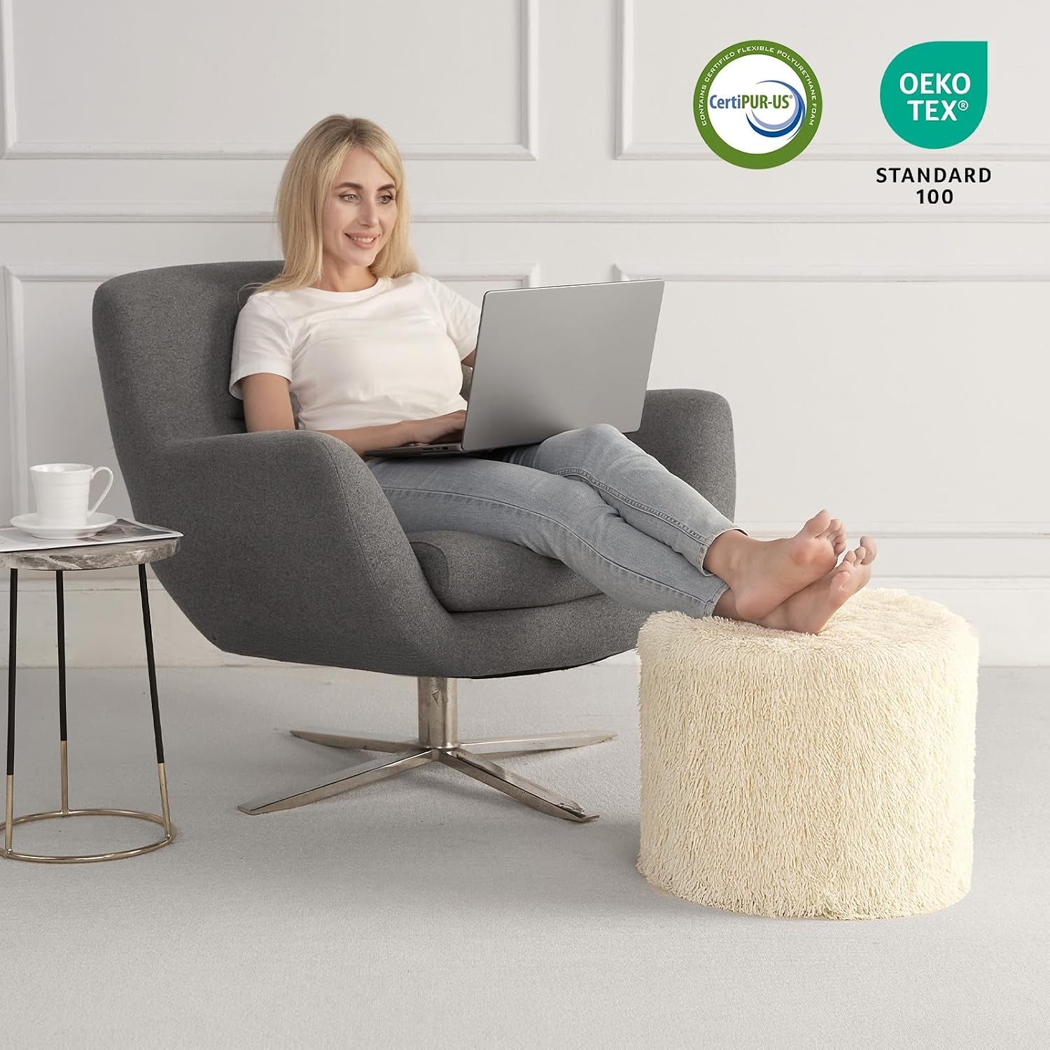 Beige faux fur pouf beside a grey swivel chair shown in a simple room setting