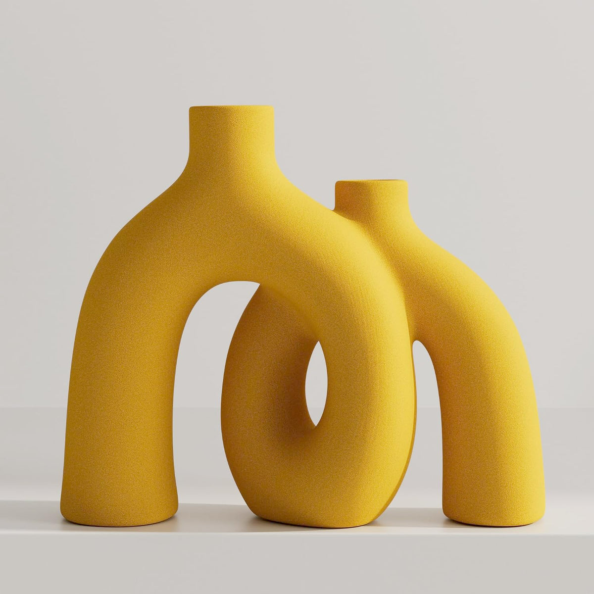 Matte yellow textured pair of double-arch donut vases displayed on a neutral surface