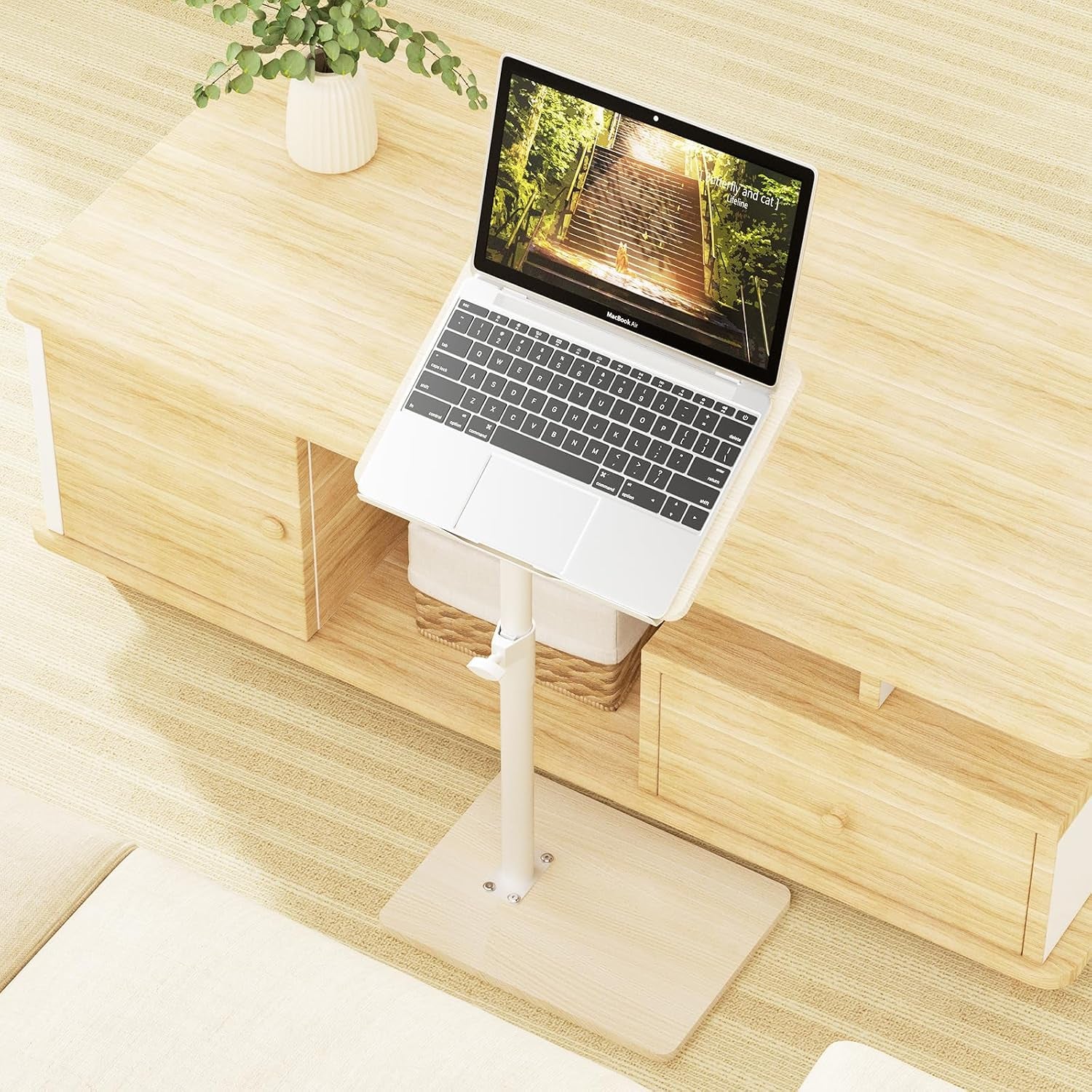 Top-down view of light wood tray table with a laptop on a tilted surface placed beside a sofa and console