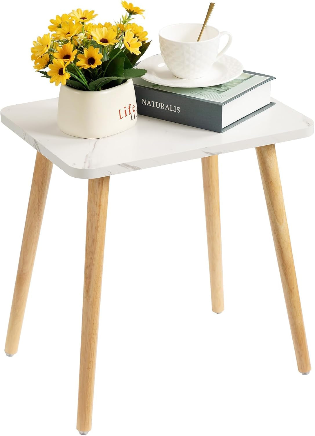 Small rectangular side table with white marble-look top and four tapered light wood legs, styled with yellow flowers, a book