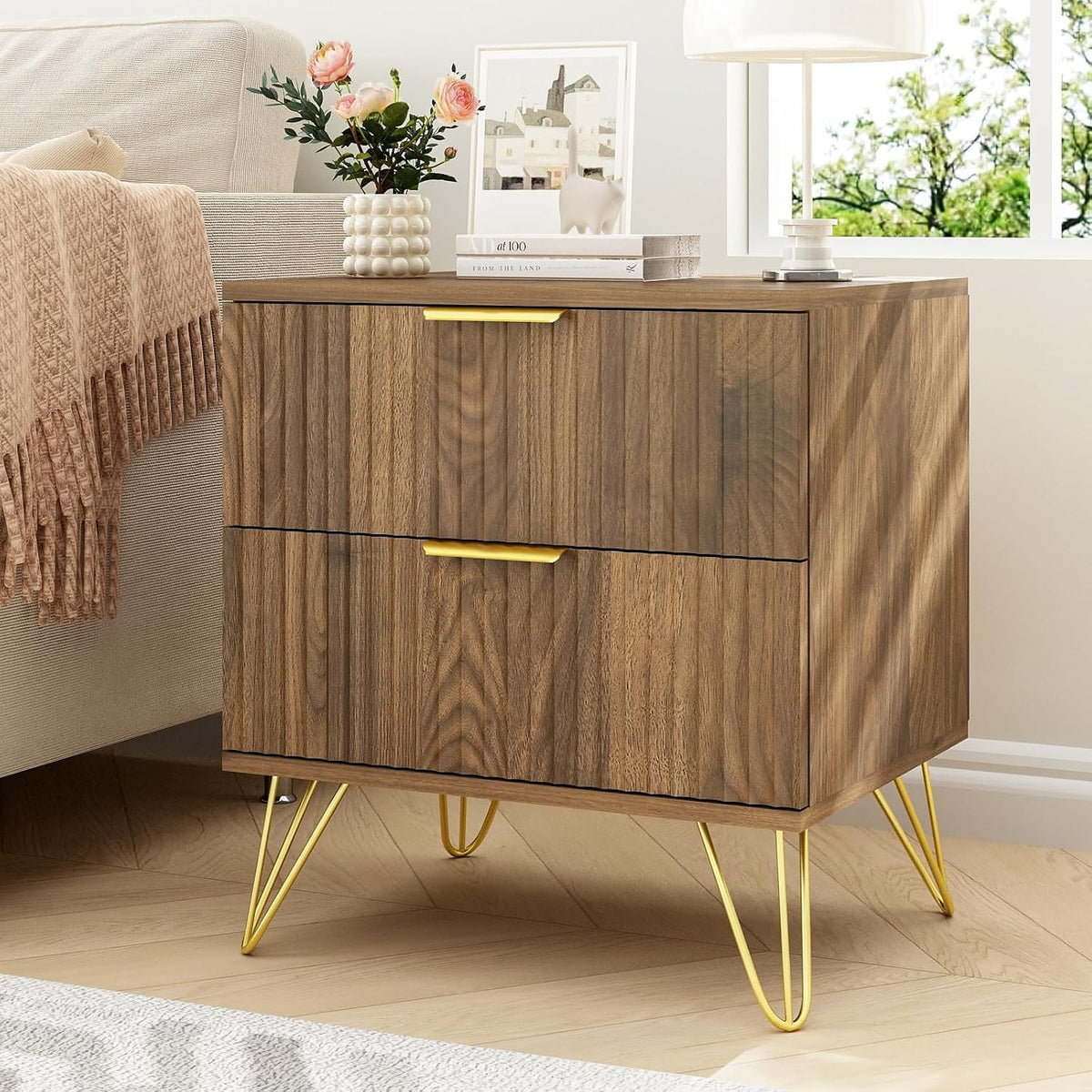 Close-up side view of a walnut nightstand with gold hairpin legs and two drawer fronts.