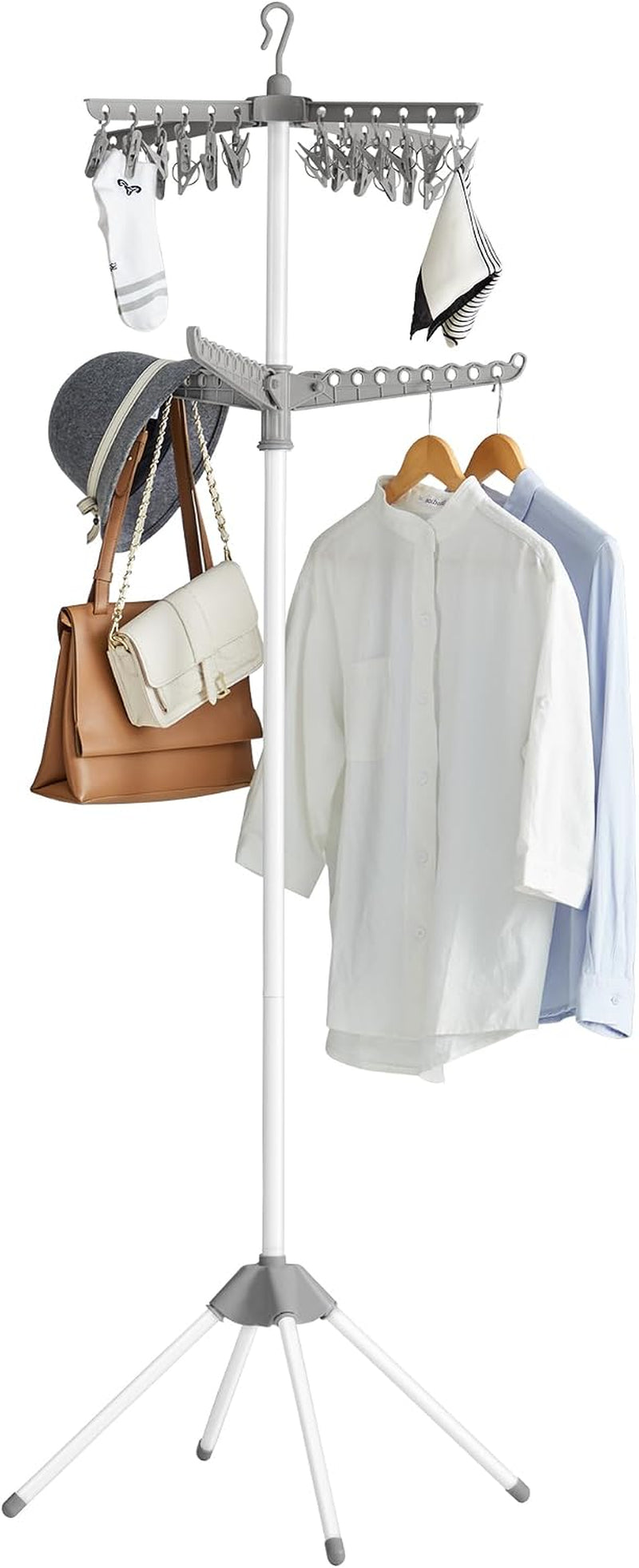 White tall drying rack showing two rotatable arms loaded with shirts, hats, purses and multiple hanging clips.