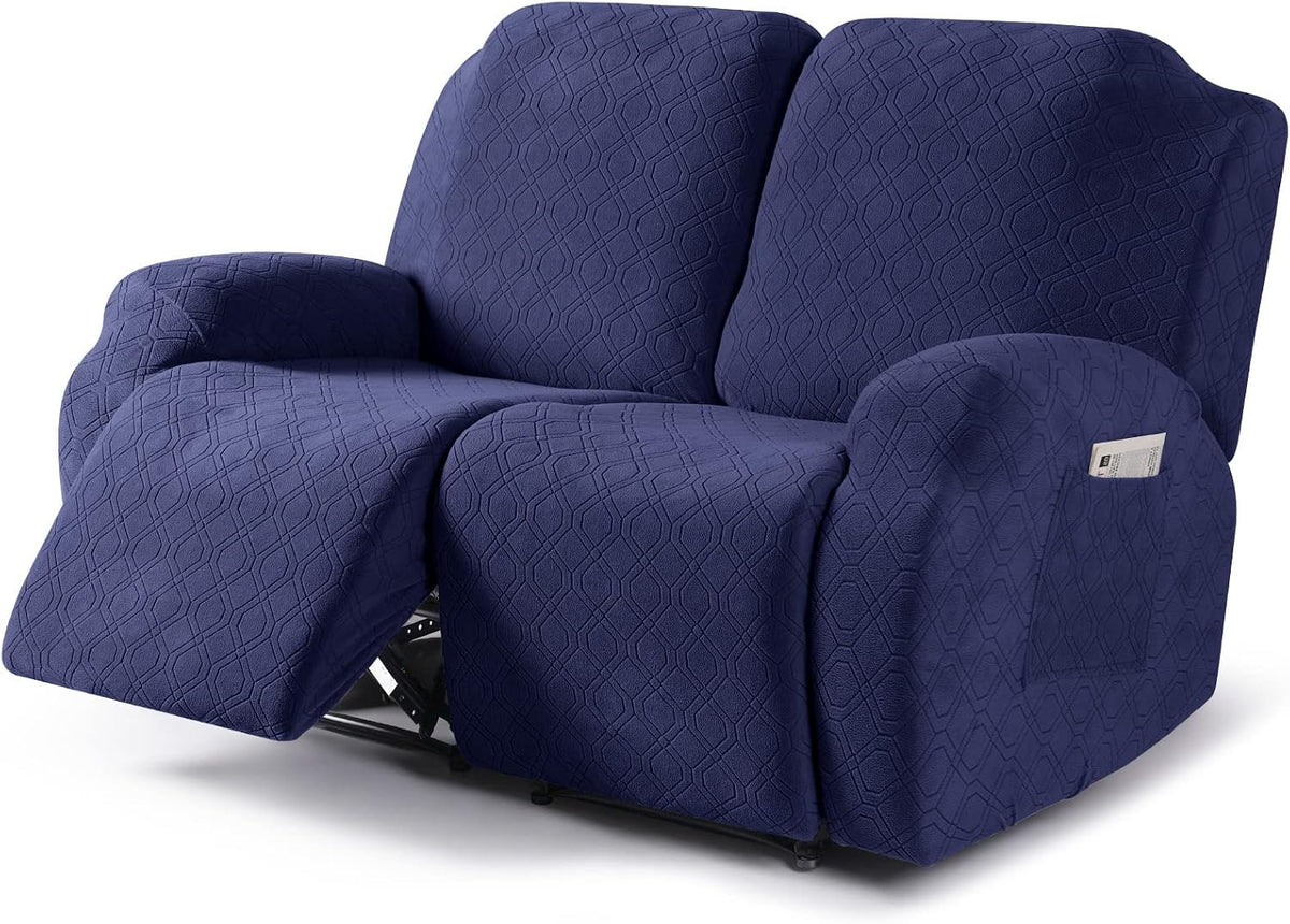Front three-quarter view of a reclining loveseat covered in a textured dark navy slipcover with one footrest extended.