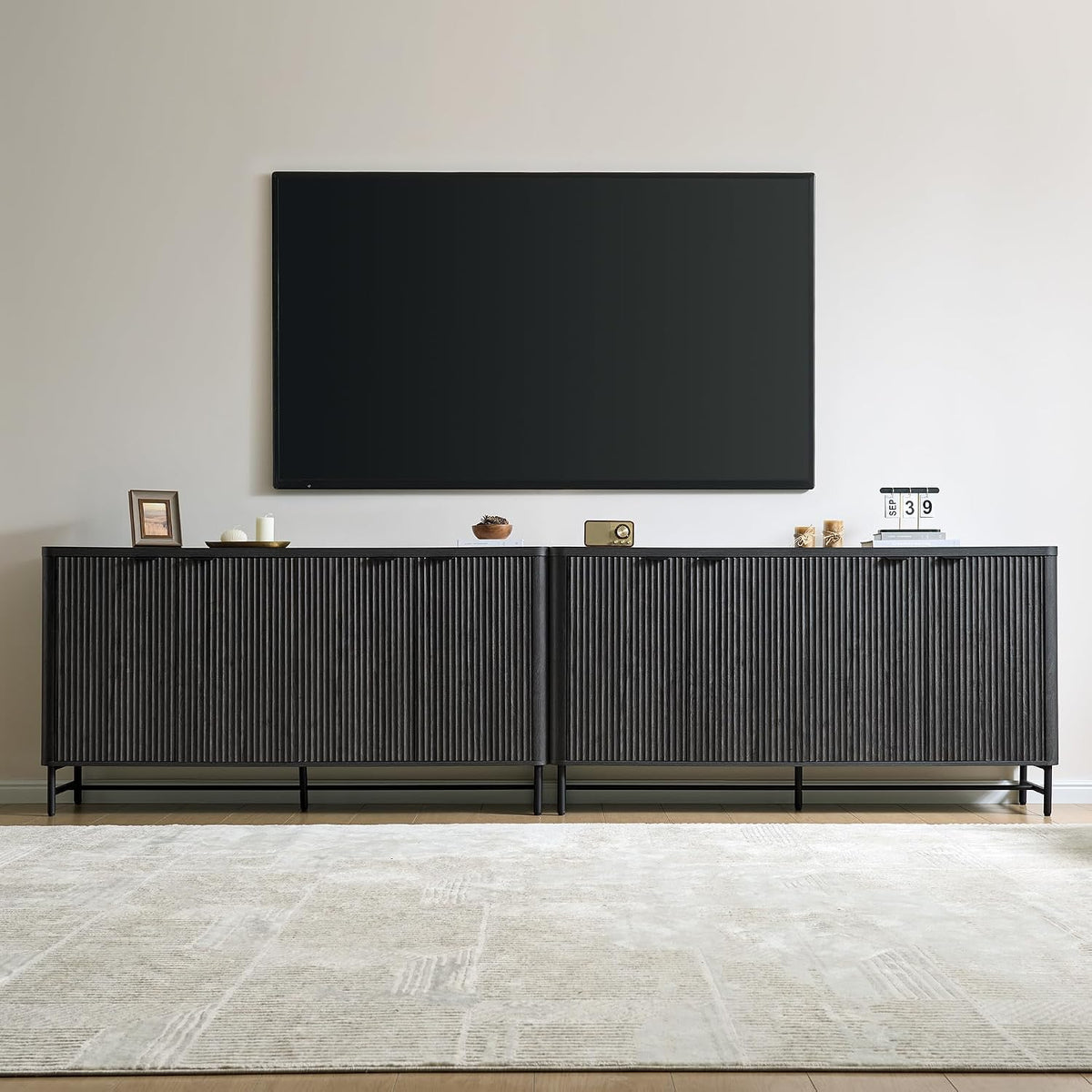 Long ribbed charcoal sideboard under a wall-mounted TV with small decor on top