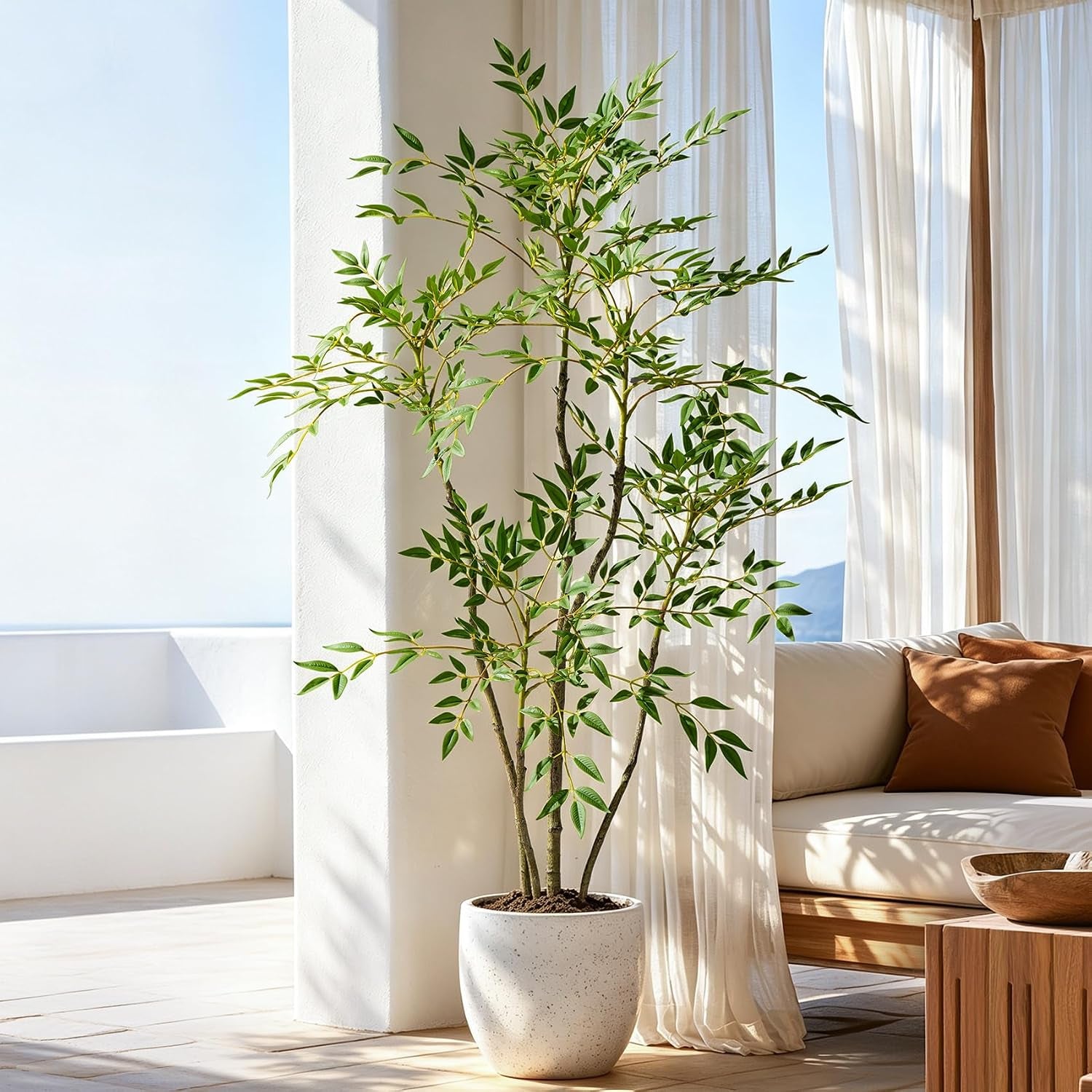 Green-leaf nandina in a speckled white planter beside a low wooden coffee table and a cream sofa with a rust pillow.