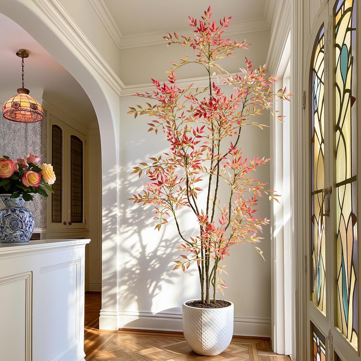 Faux Nandina tree with orange-red leaves in white textured planter, tall front view in an entryway