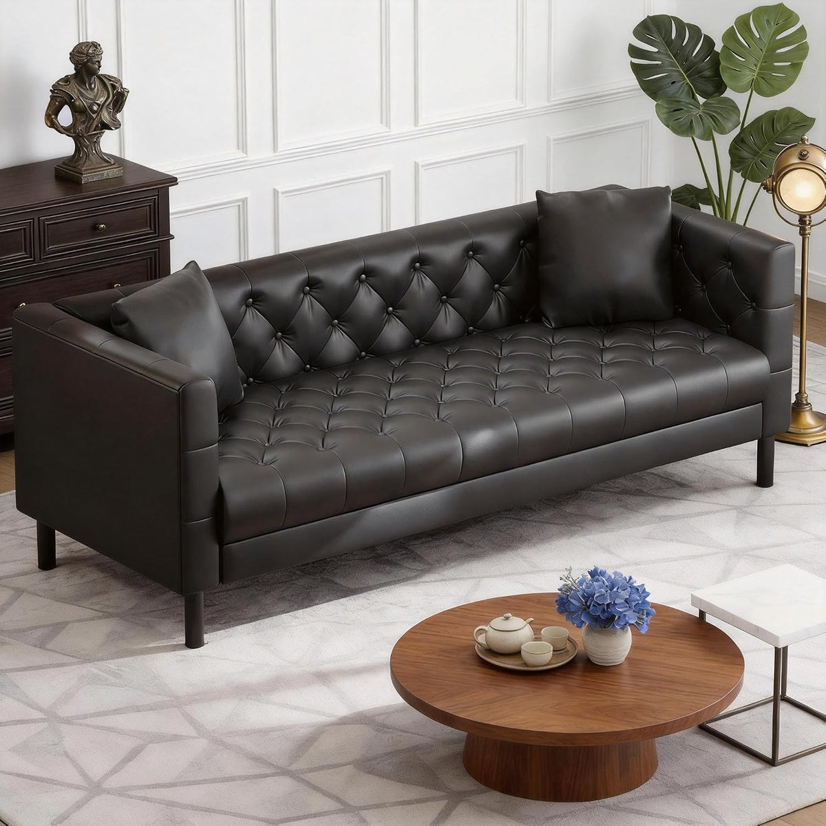 Tufted three-seat faux leather sofa in cognac tan with two square pillows, staged in a living room.