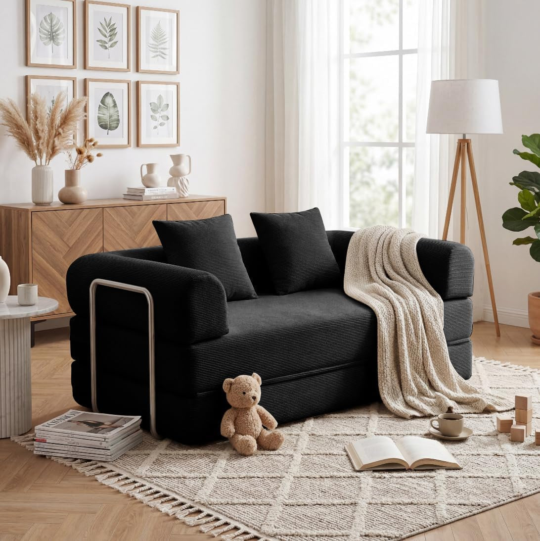 Black corduroy convertible sofa bed with throw draped over arm and plush pillow in cozy room