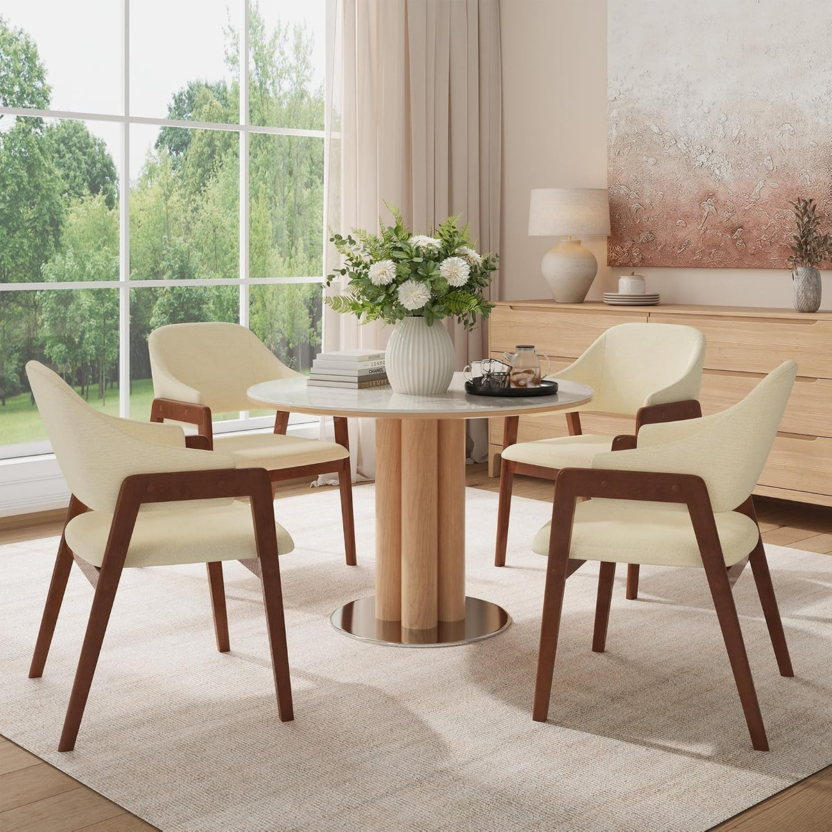 Four cream dining chairs shown from a three-quarter angle around a small round table on a neutral area rug.