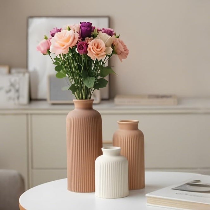Set of three matte-finish ribbed vases arranged on a round table with florals in the tallest vase.