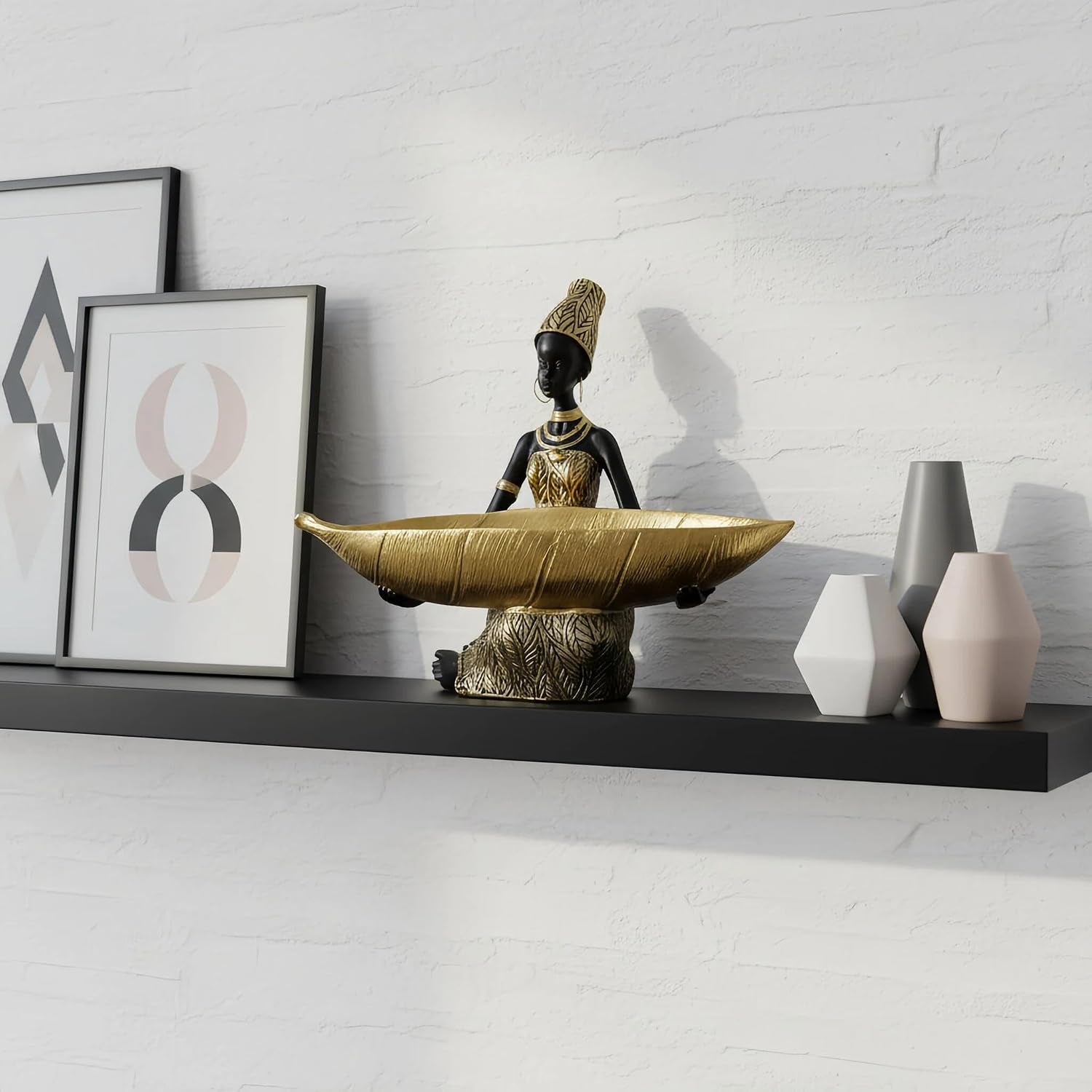 African woman resin tray statue shown on a black floating shelf with framed abstract prints and small decorative vases