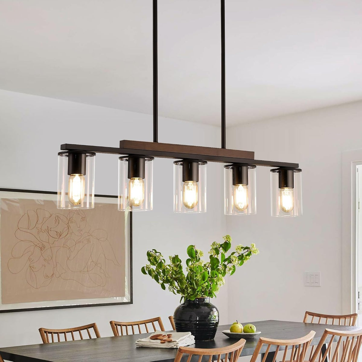 Side view of the linear chandelier with clear glass shades and black rods suspended over a dining room