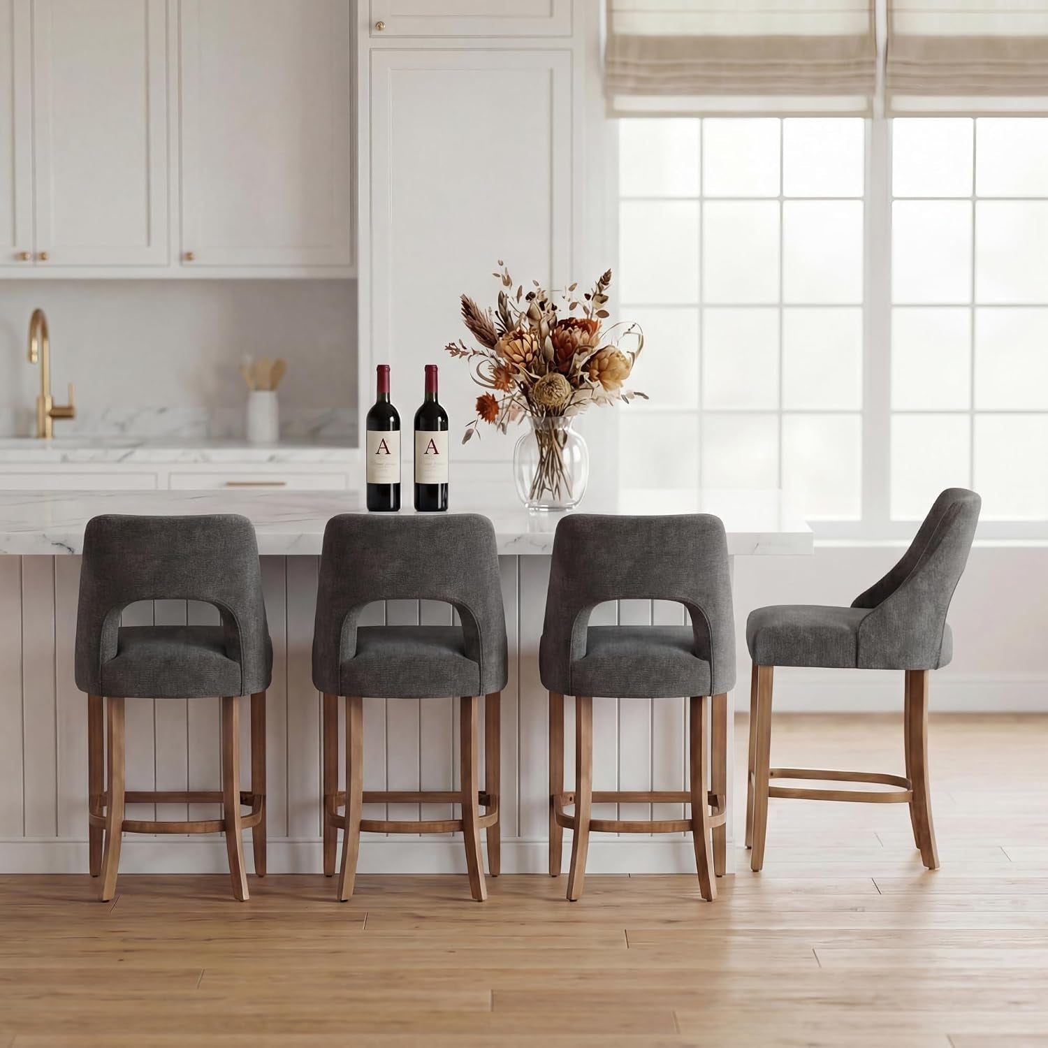 Three charcoal-gray counter stools plus one side view, all upholstered with wood bases at a bright island