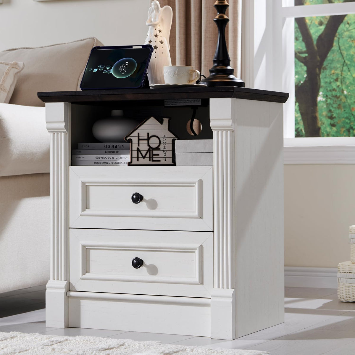 Angled view of an antique-white nightstand showing an open shelf above two drawers and a dark top.