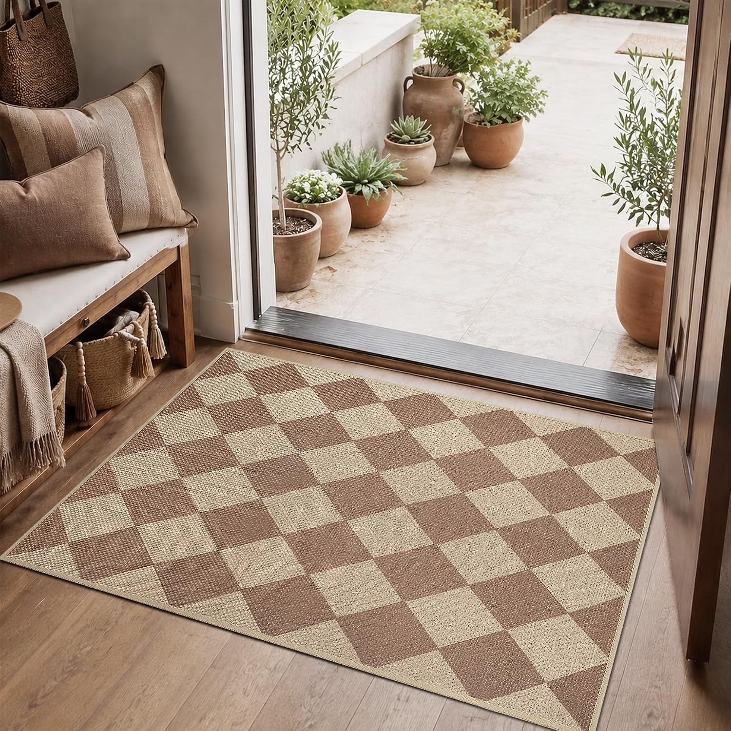 Brown-and-beige checkered rug laid at an open doorway with a bench and potted plants outside.