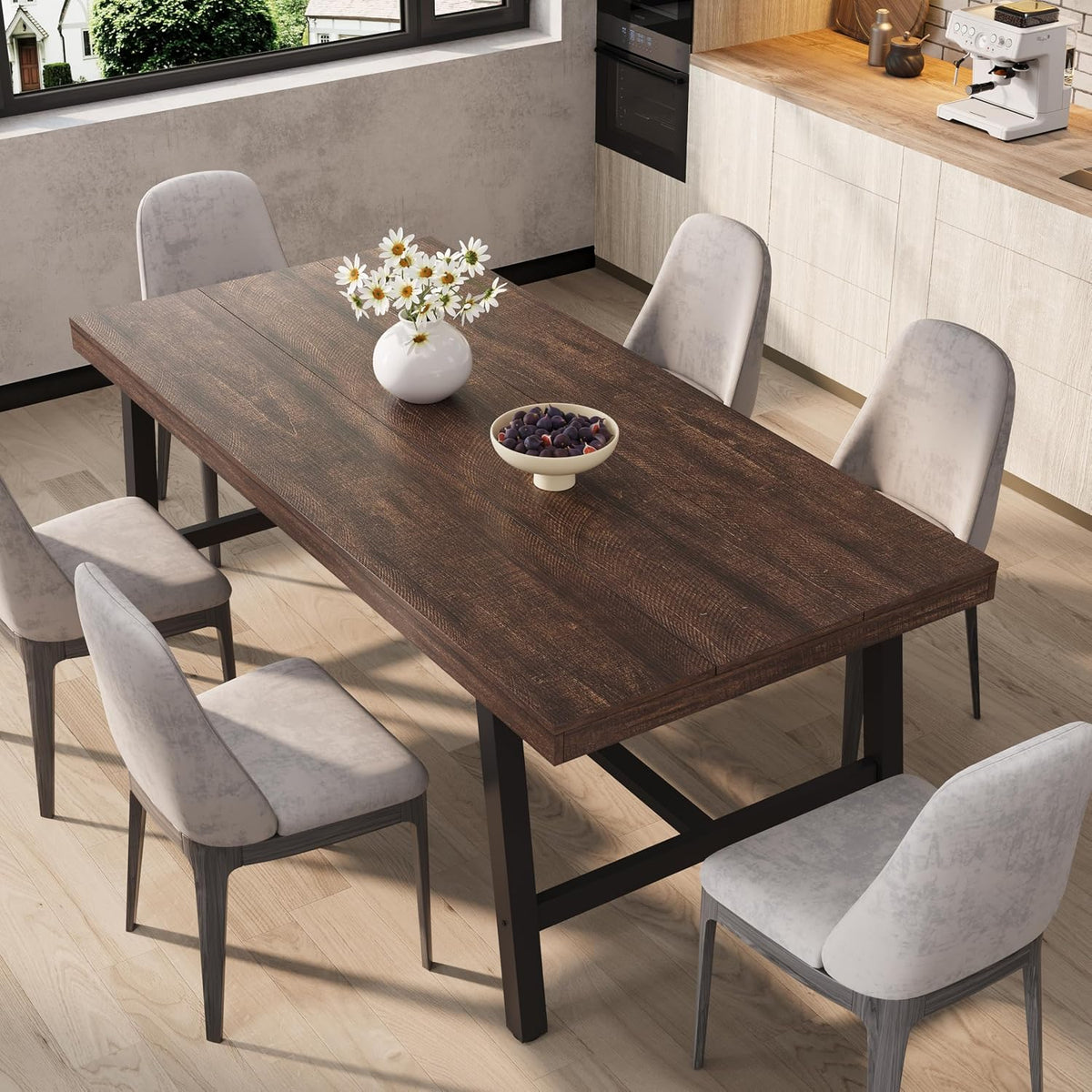 Rectangular dining table in a warm dark brown wood finish with black metal base and chairs around it.