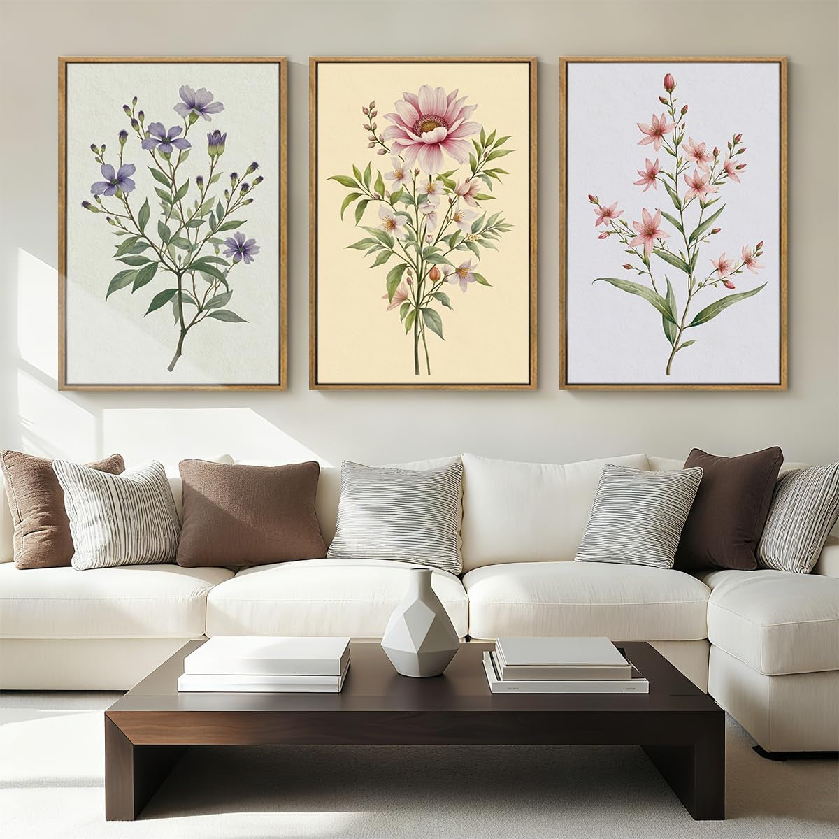 Living room wall above a cream sectional showing three floral prints in wood frames, coffee table and pillows below.