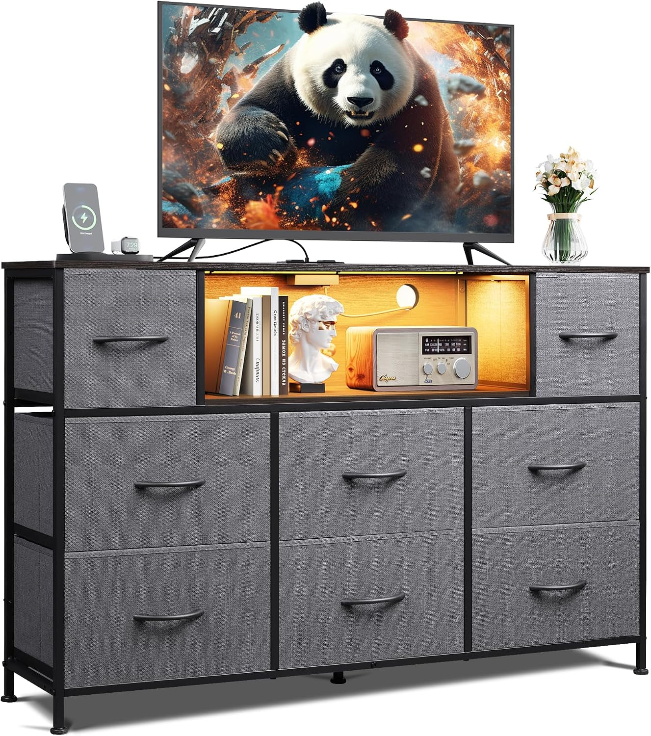 Front view of a dark gray fabric 8-drawer dresser with lit center cubby and television above