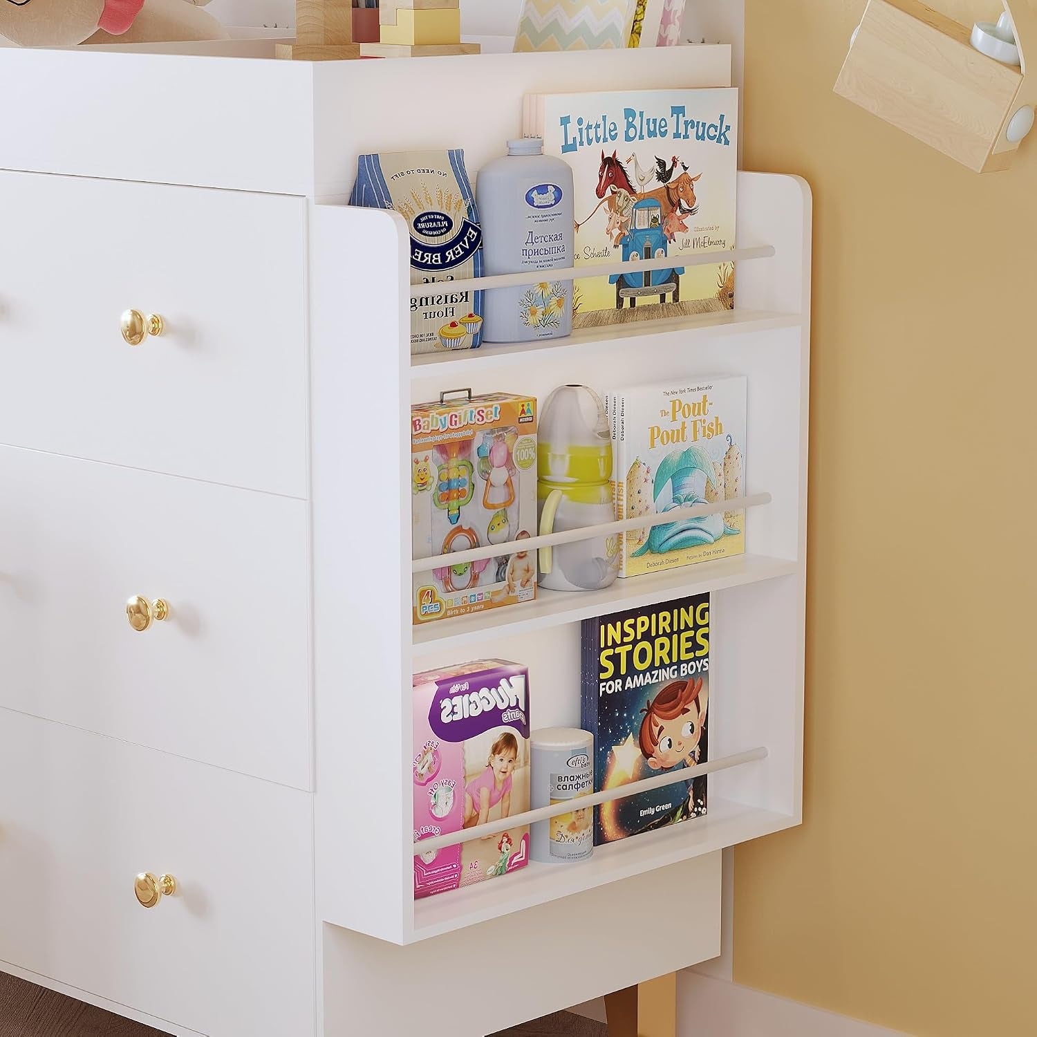 Close-up of the narrow side bookshelf stocked with children's books, a bottle and a box of diapers.