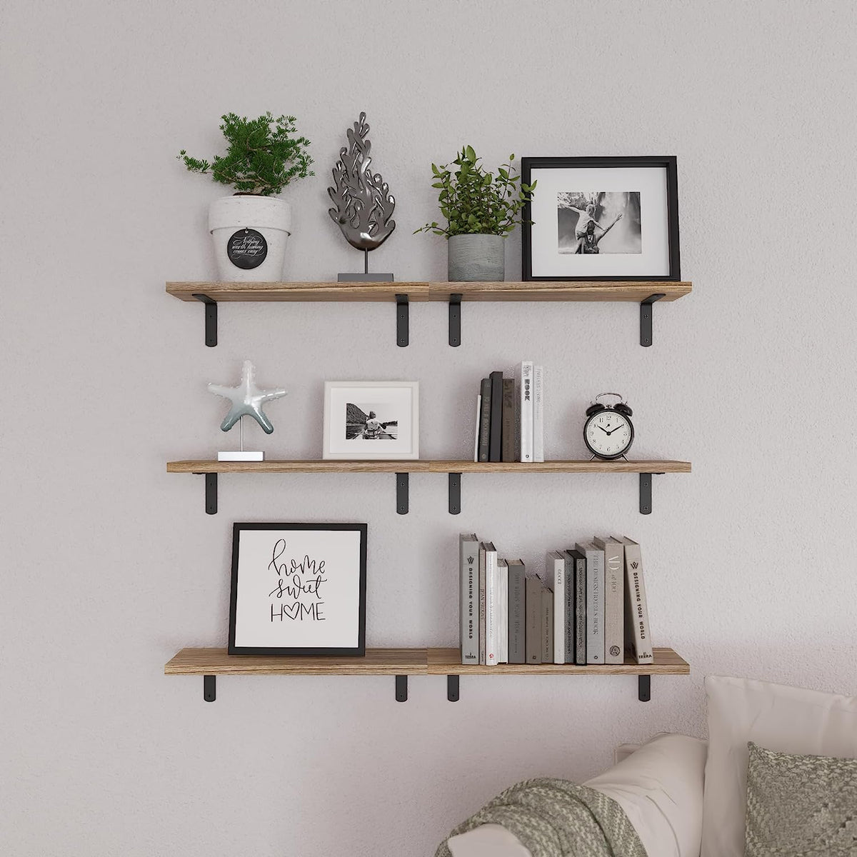 Three horizontal rustic floating shelves mounted on a living room wall displaying books, frames, and decor