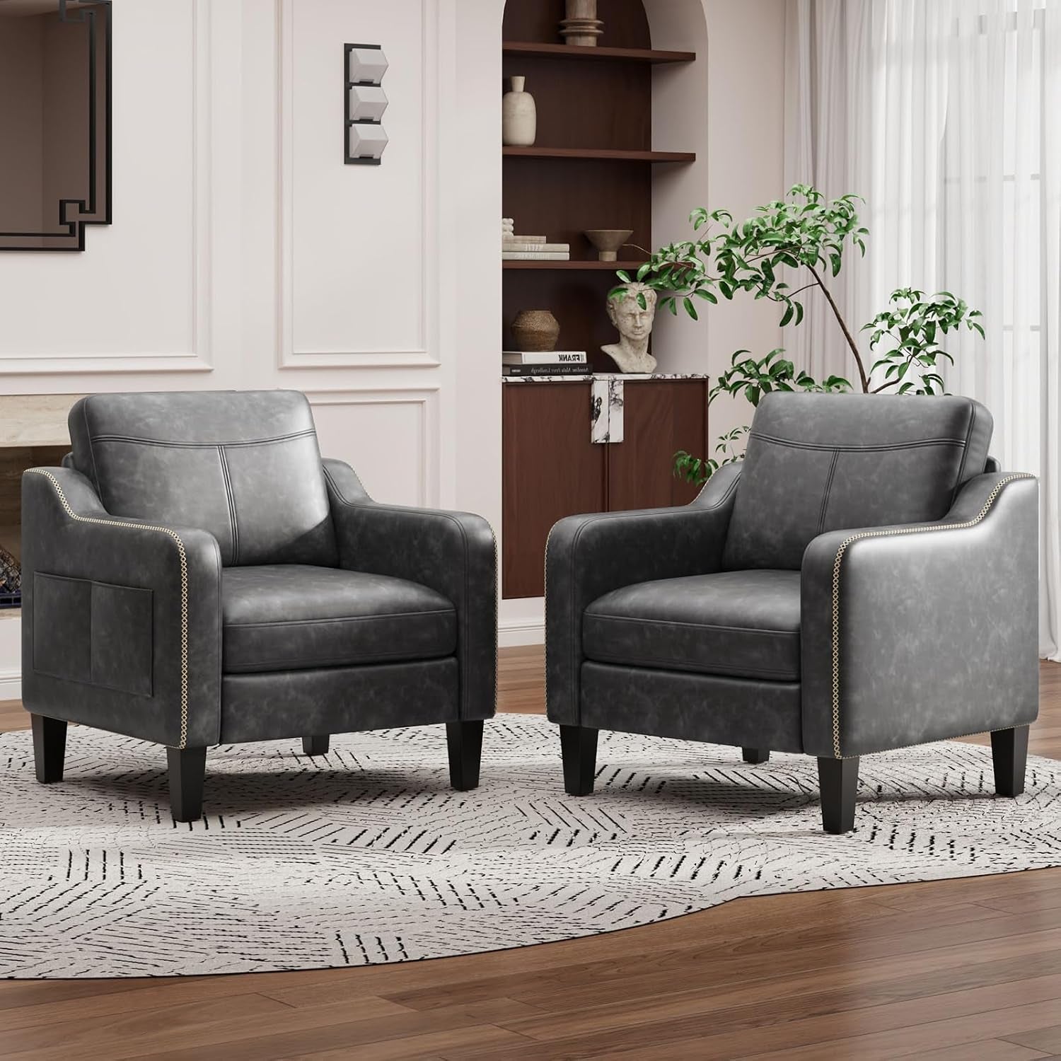 Two gray armchairs with nailhead trim on a round rug in a softly lit room.