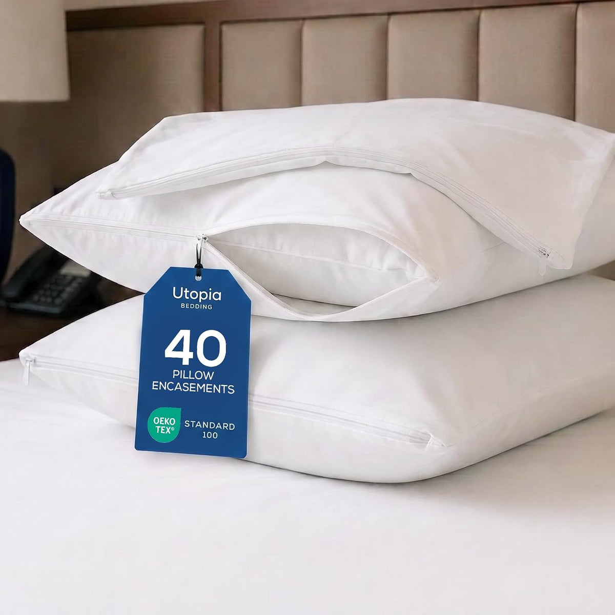 Close-up of stacked pillow protectors with a zipper open on one and a hanging blue tag.