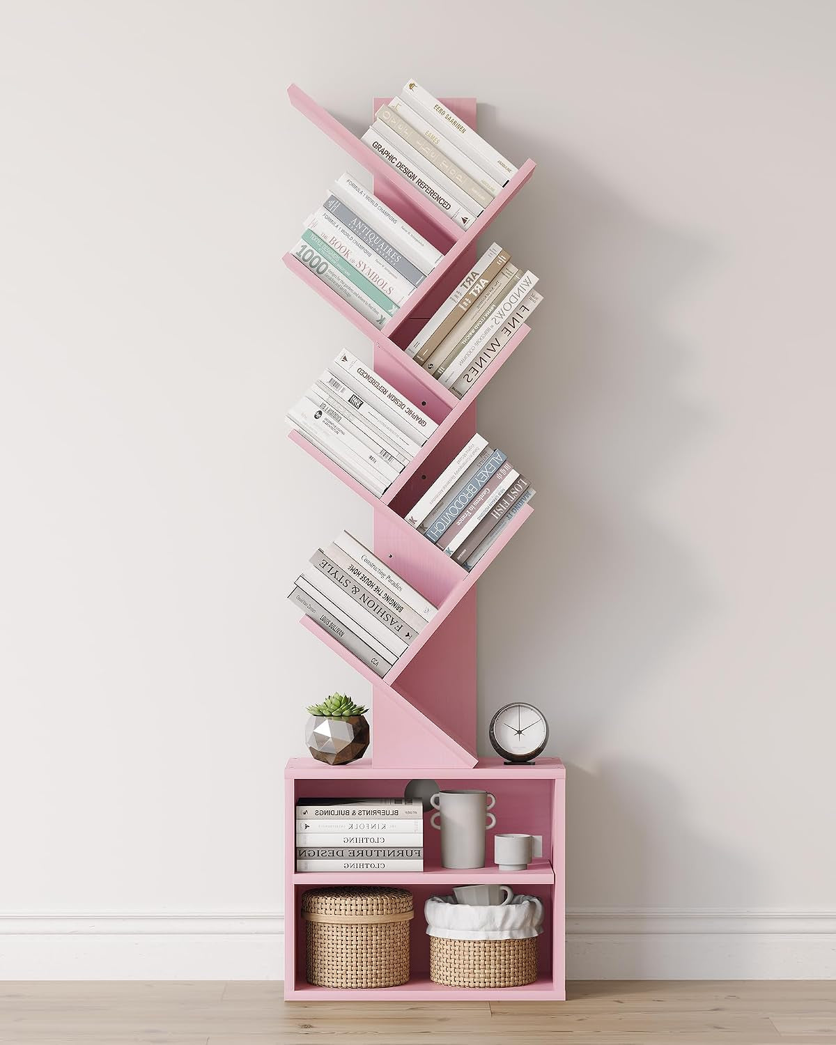 Pink six-tier tree bookshelf styled with books, a plant and woven baskets on the bottom cubbies.