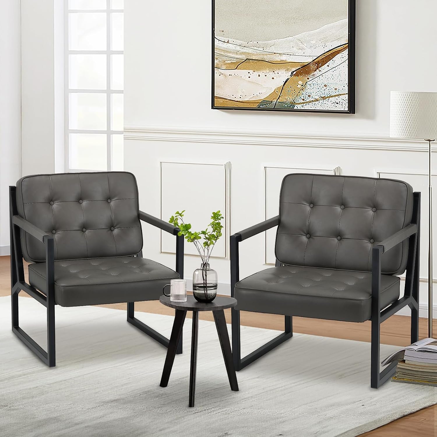 Set of two dark gray tufted chairs with black frames arranged around a small tripod side table