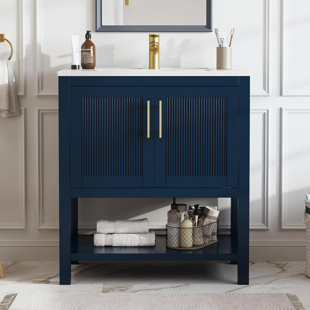 Navy blue freestanding bathroom vanity with white top, gold faucet and handles, fluted double doors and lower open shelf