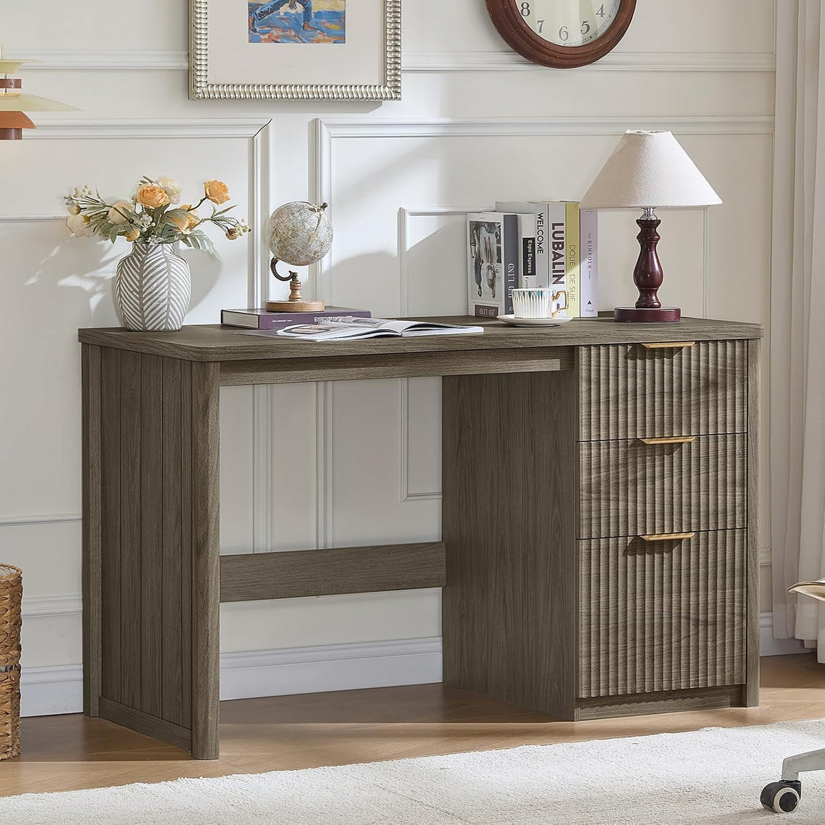 Weathered gray wood desk with textured drawer fronts and vase, globe, and lamp on top
