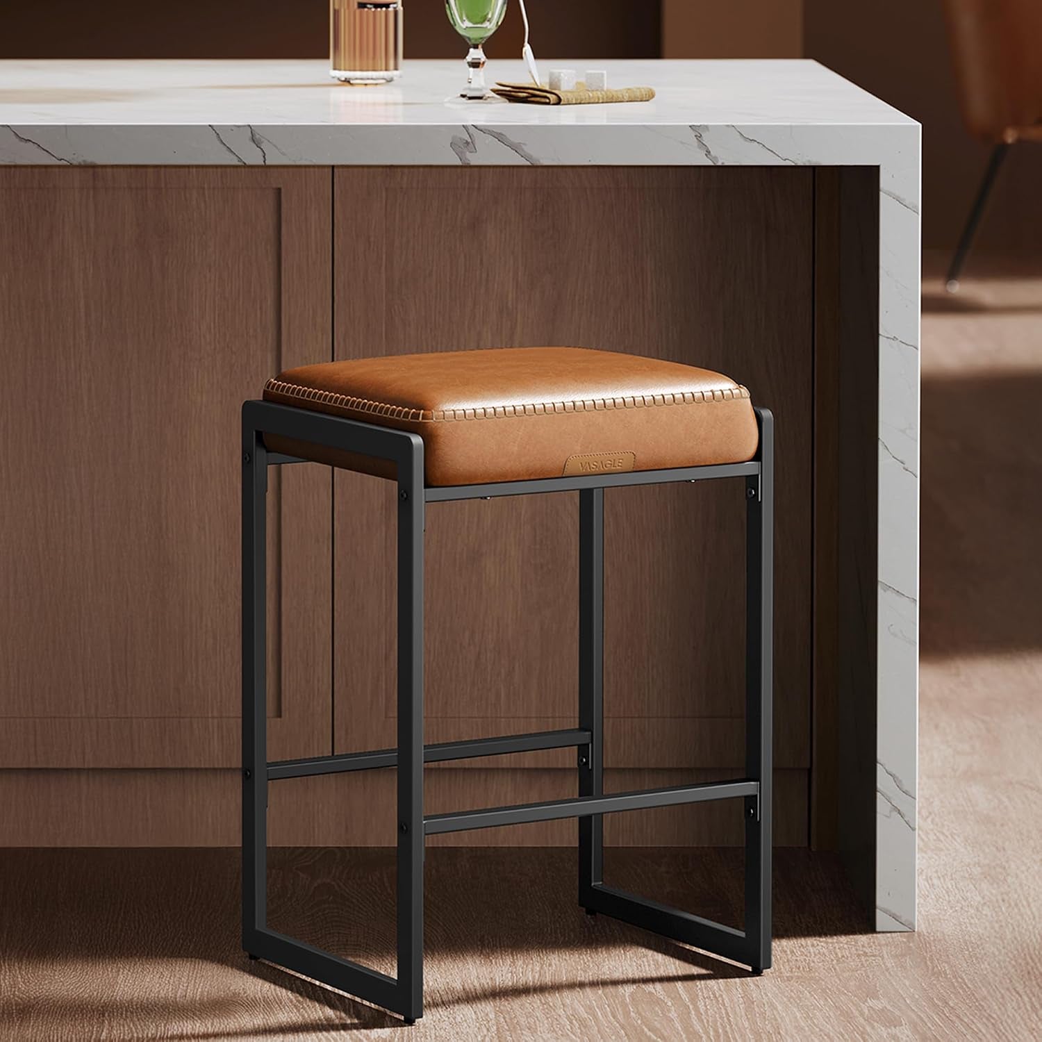 Side view close-up of a single caramel PU cushion on a matte black rectangular metal stool frame.