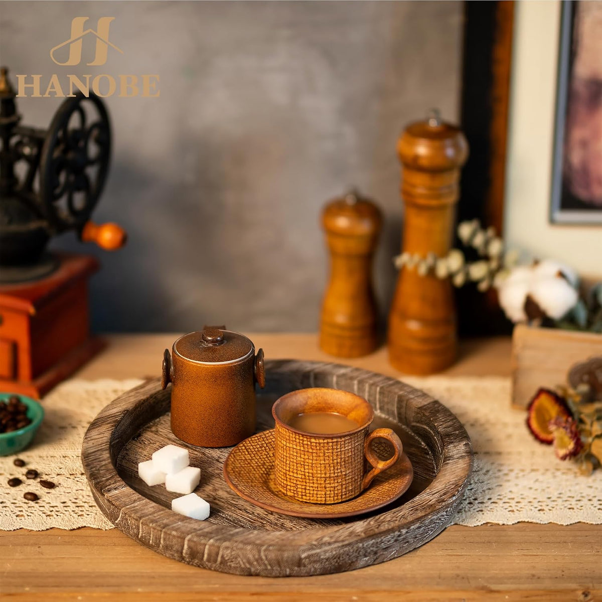 Round wooden tray styled with a teacup, sugar cubes and a ceramic jar on a farmhouse tabletop