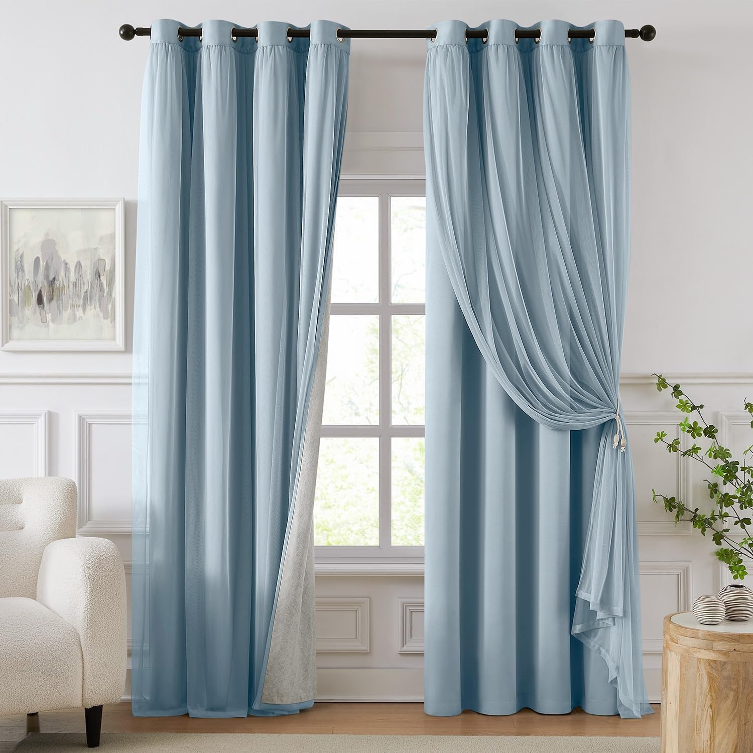 Pale blue blackout curtains paired with a matching sheer overlay pulled to one side at a window.