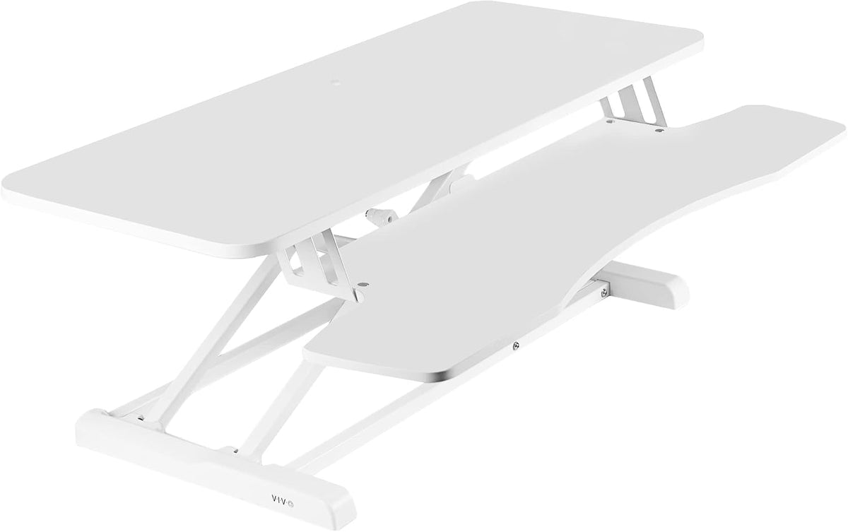 Angled view of a white two-tier standing desk converter with keyboard shelf and scissor lift frame.